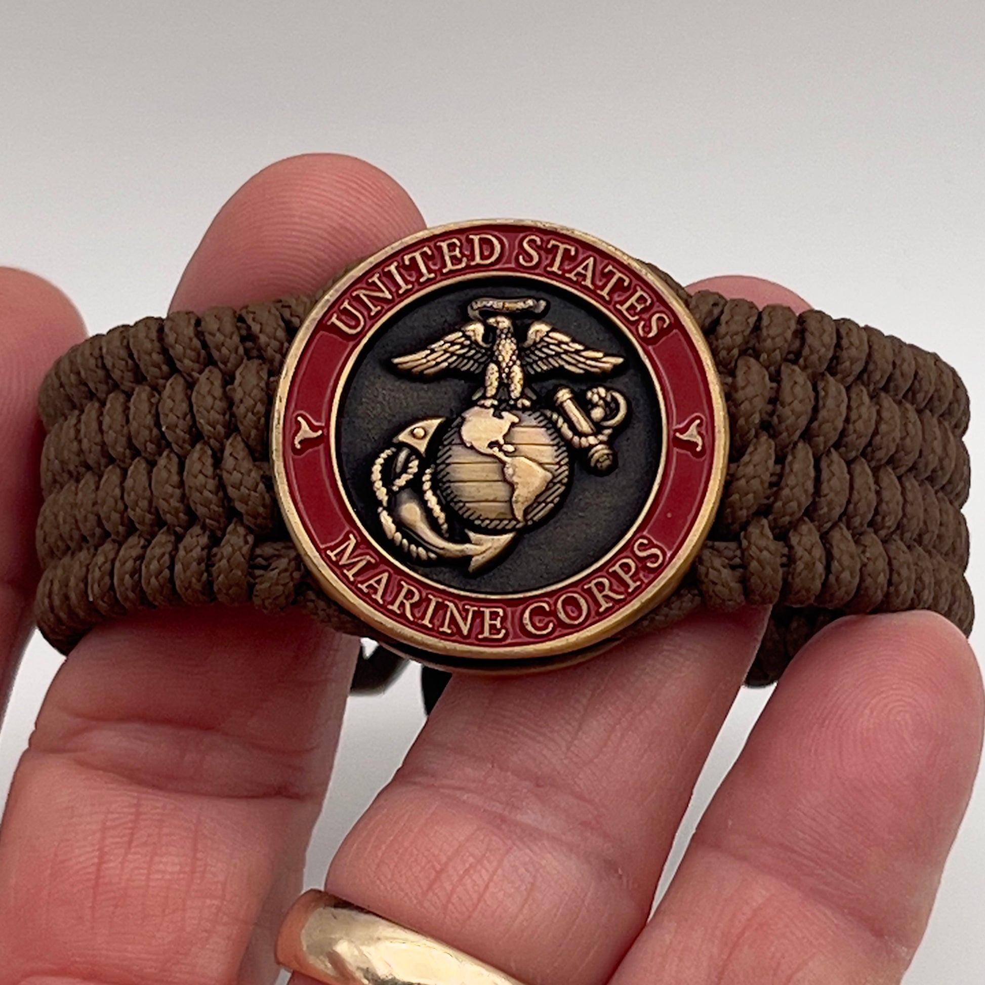 Thin, medium wide, flexible and comfortable braided United States Marine Corps bracelet featuring a 24K antique gold plated USMC Eagle Globe and Anchor medallion, a gold Cobra style tactical buckle and woven with Coyote Brown Type-1 paracord.