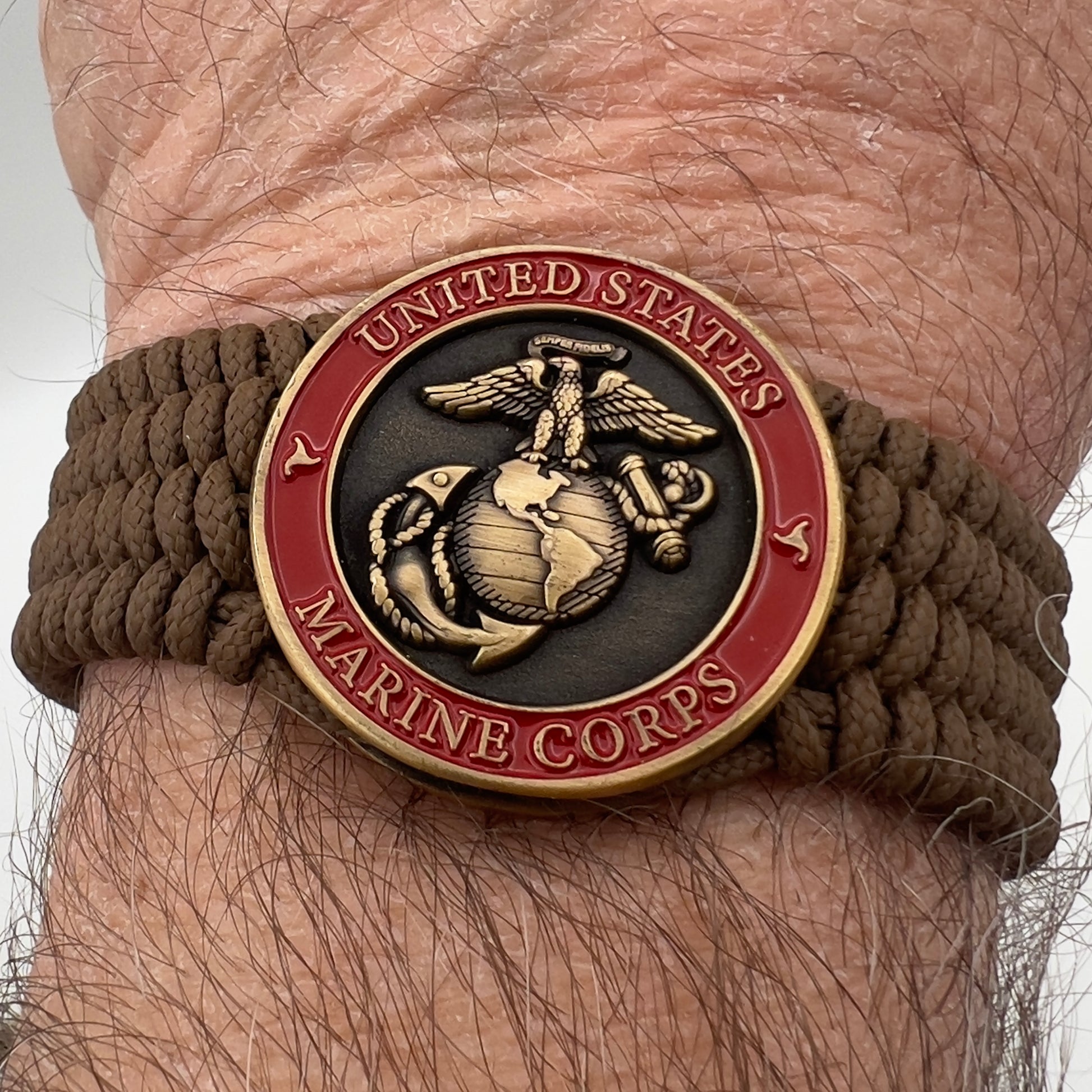 Thin, medium wide, flexible and comfortable braided United States Marine Corps bracelet featuring a 24K antique gold plated USMC Eagle Globe and Anchor medallion, a gold Cobra style tactical buckle and woven with Coyote Brown Type-1 paracord.