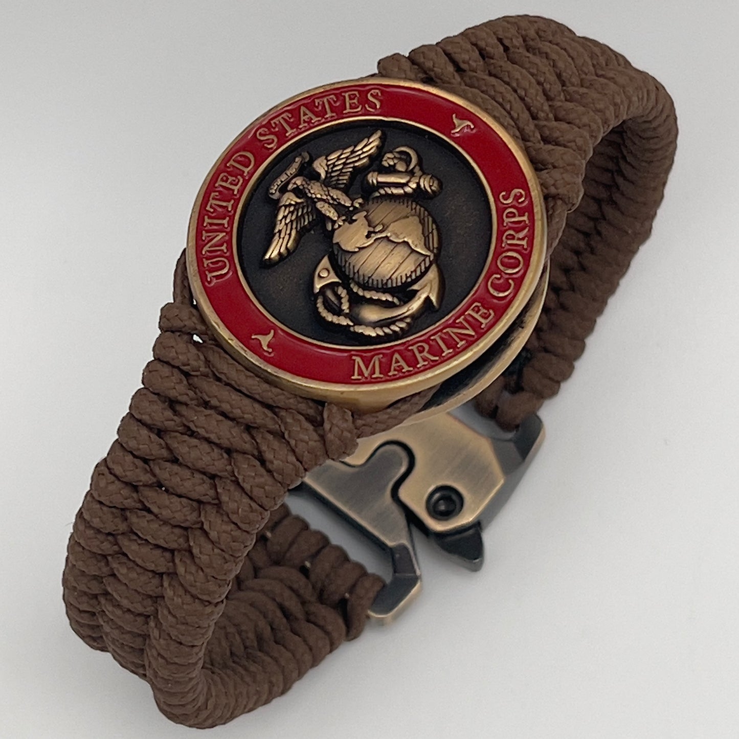 Thin, narrow, flexible and comfortable braided United States Marine Corps bracelet featuring a 24K antique gold plated USMC Eagle Globe and Anchor medallion, a gold Cobra style tactical buckle and woven with Coyote Brown Type-1 paracord.