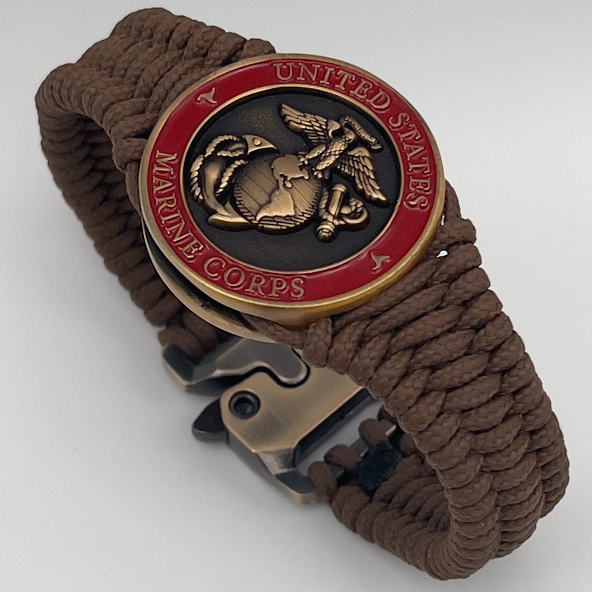 Thin, narrow, flexible and comfortable braided United States Marine Corps bracelet featuring a 24K antique gold plated USMC Eagle Globe and Anchor medallion, a gold Cobra style tactical buckle and woven with Coyote Brown Type-1 paracord.