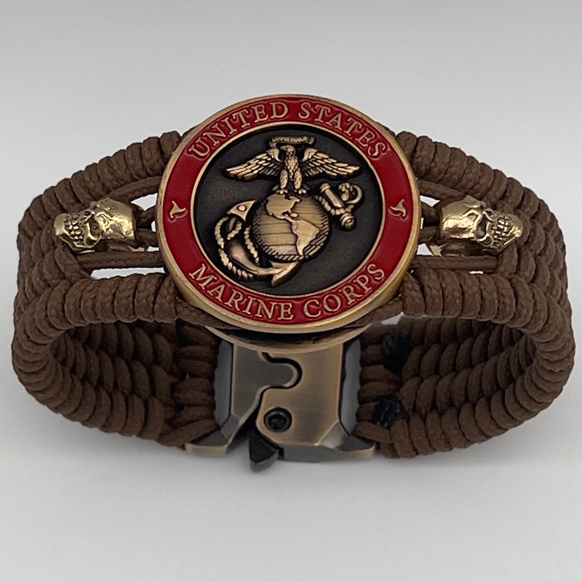 Thin, medium width, flexible and comfortable braided United States Marine Corps bracelet featuring a 24K antique gold plated USMC officer Eagle Globe and Anchor medallion, two gold plated skulls, a gold Cobra style tactical buckle and woven with Coyote Brown Type-1 paracord.