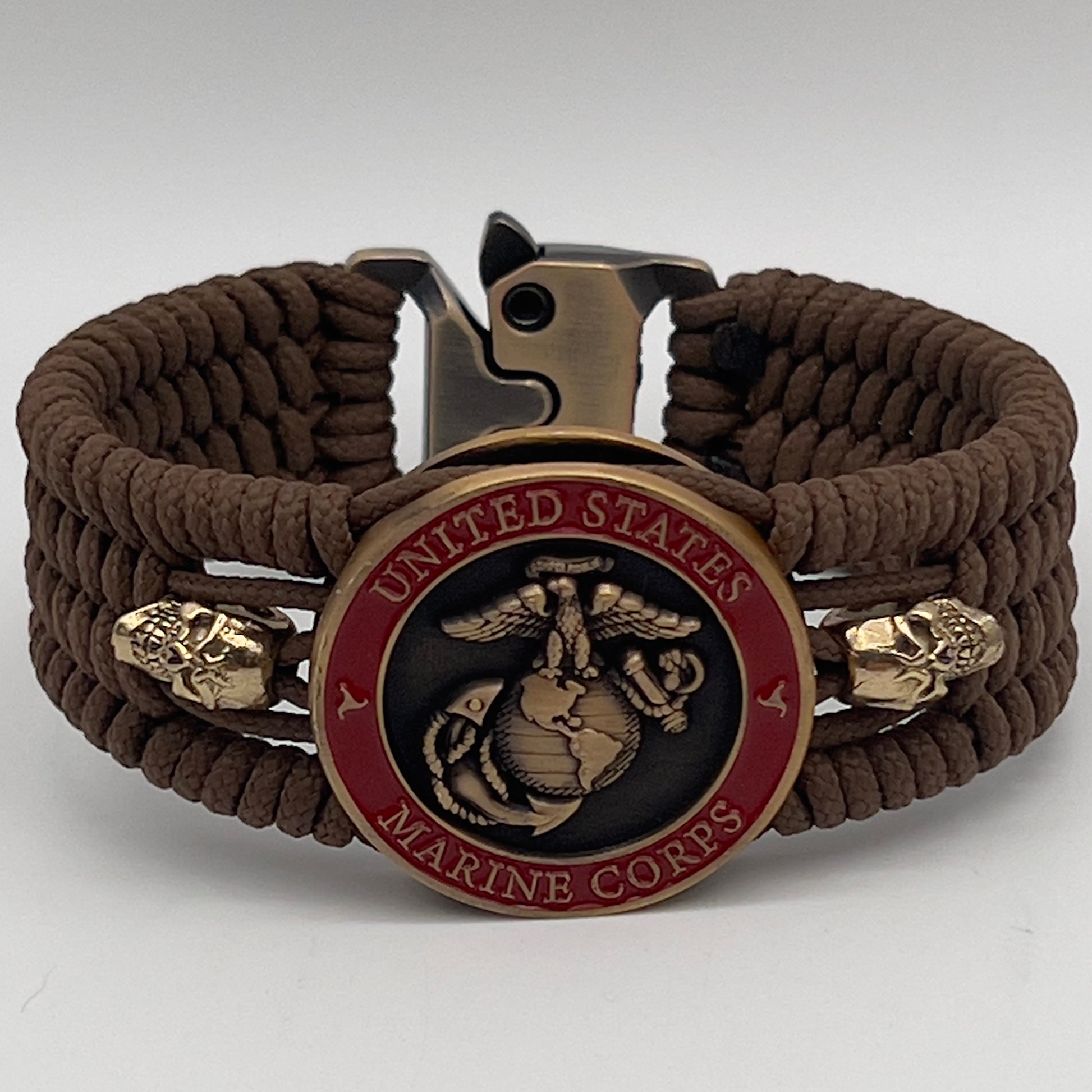 Thin, medium width, flexible and comfortable braided United States Marine Corps bracelet featuring a 24K antique gold plated USMC officer Eagle Globe and Anchor medallion, two gold plated skulls, a gold Cobra style tactical buckle and woven with Coyote Brown Type-1 paracord.