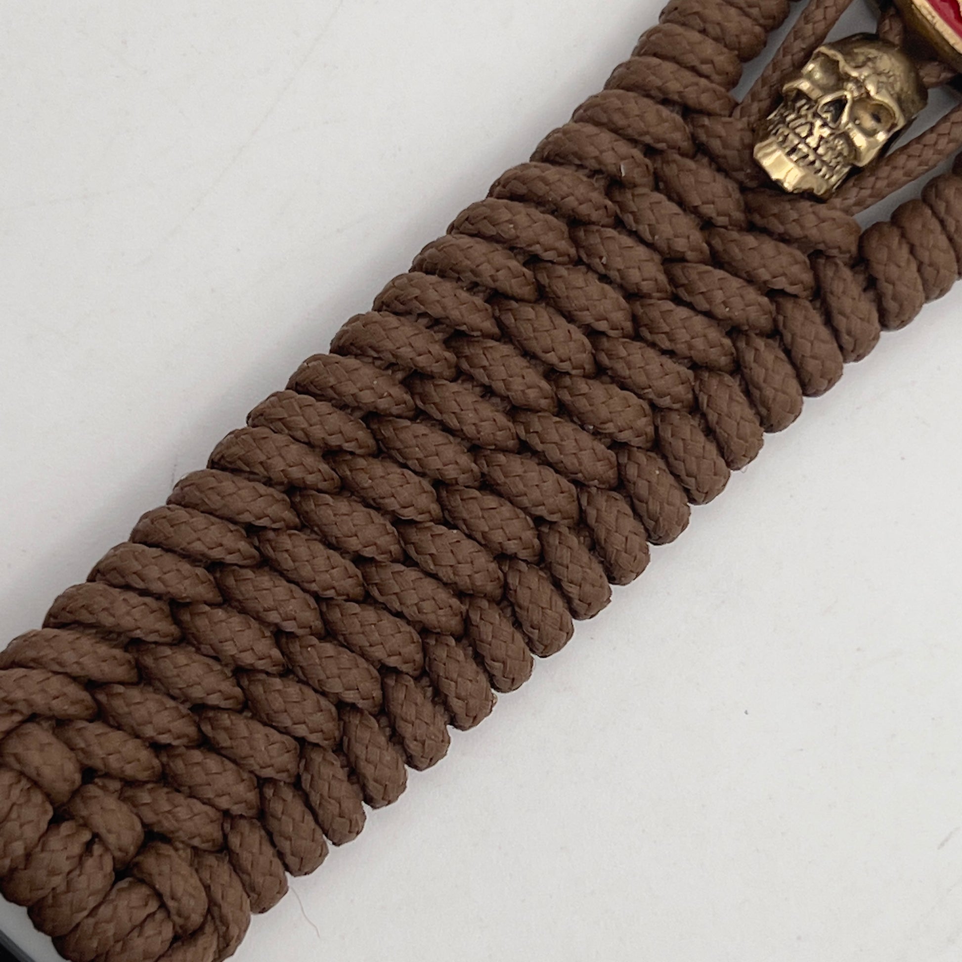 Thin, medium width, flexible and comfortable braided United States Marine Corps bracelet featuring a 24K antique gold plated USMC officer Eagle Globe and Anchor medallion, two gold plated skulls, a gold Cobra style tactical buckle and woven with Coyote Brown Type-1 paracord.