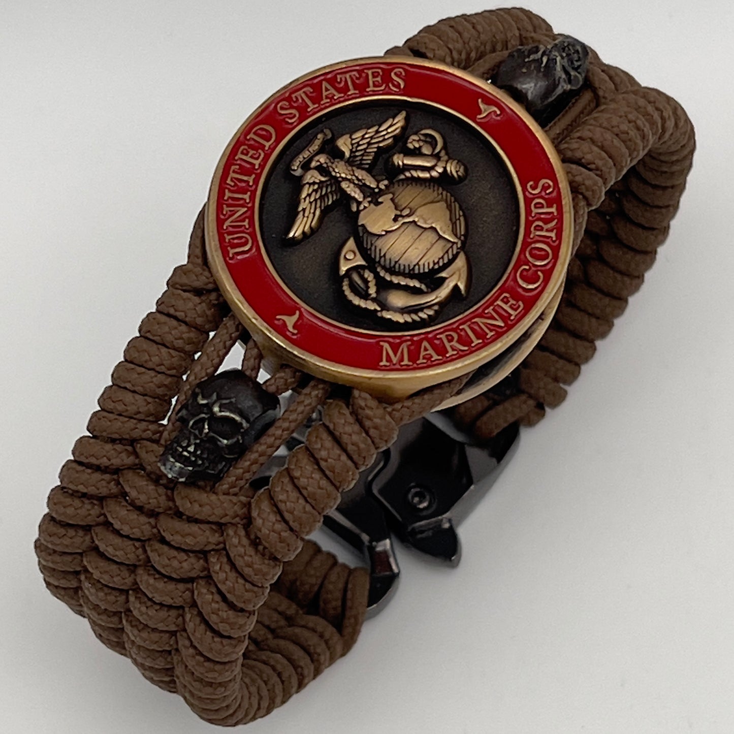 Thin, medium width, flexible and comfortable braided United States Marine Corps bracelet featuring a 24K antique gold plated USMC officer Eagle Globe and Anchor medallion, two black skulls, a black Cobra style tactical buckle and woven with Coyote Brown Type-1 paracord.