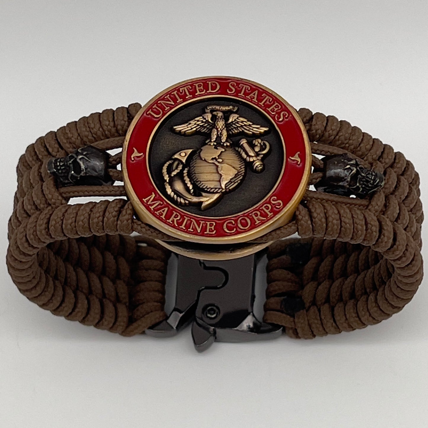 Thin, medium width, flexible and comfortable braided United States Marine Corps bracelet featuring a 24K antique gold plated USMC officer Eagle Globe and Anchor medallion, two black skulls, a black Cobra style tactical buckle and woven with Coyote Brown Type-1 paracord.