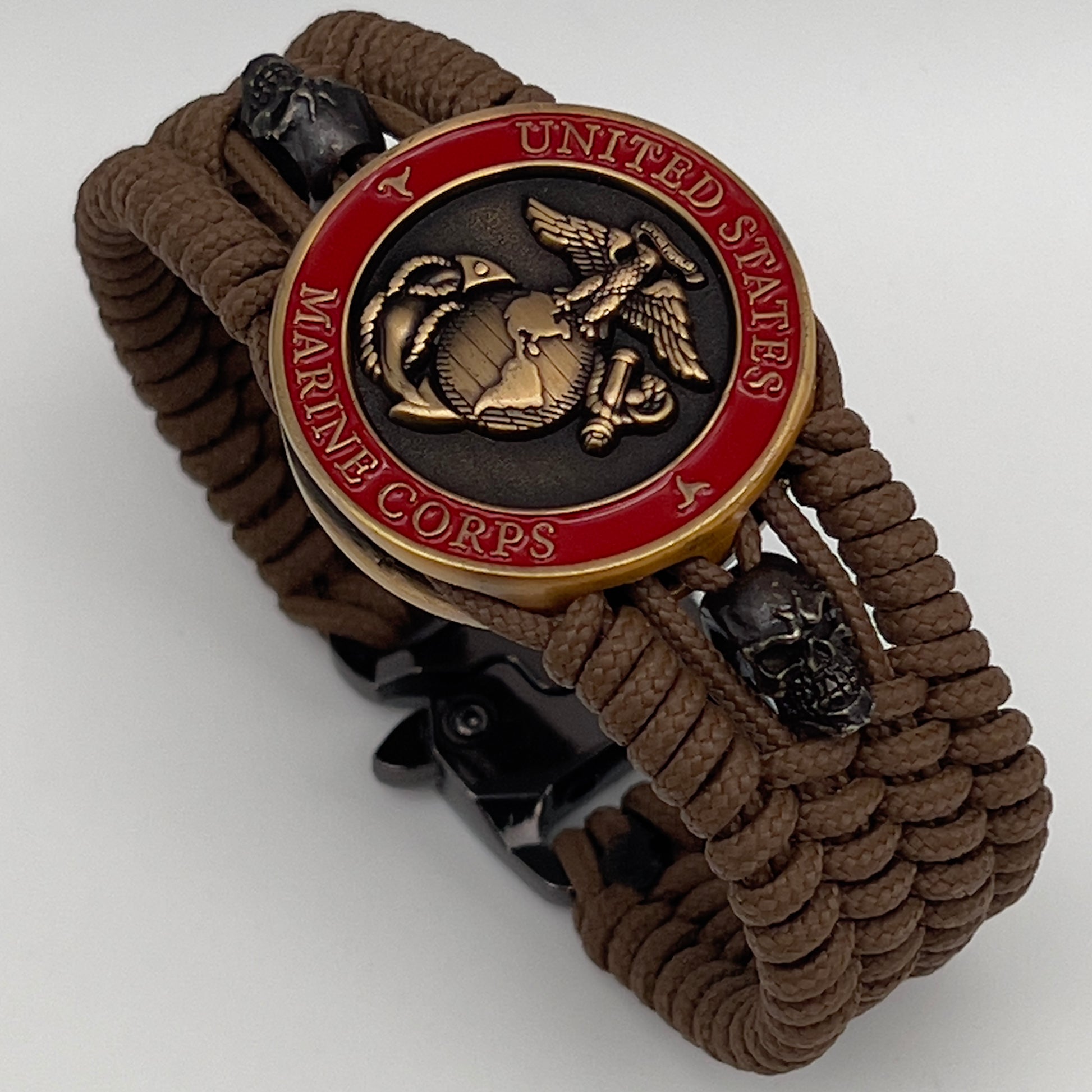 Thin, medium width, flexible and comfortable braided United States Marine Corps bracelet featuring a 24K antique gold plated USMC officer Eagle Globe and Anchor medallion, two black skulls, a black Cobra style tactical buckle and woven with Coyote Brown Type-1 paracord.
