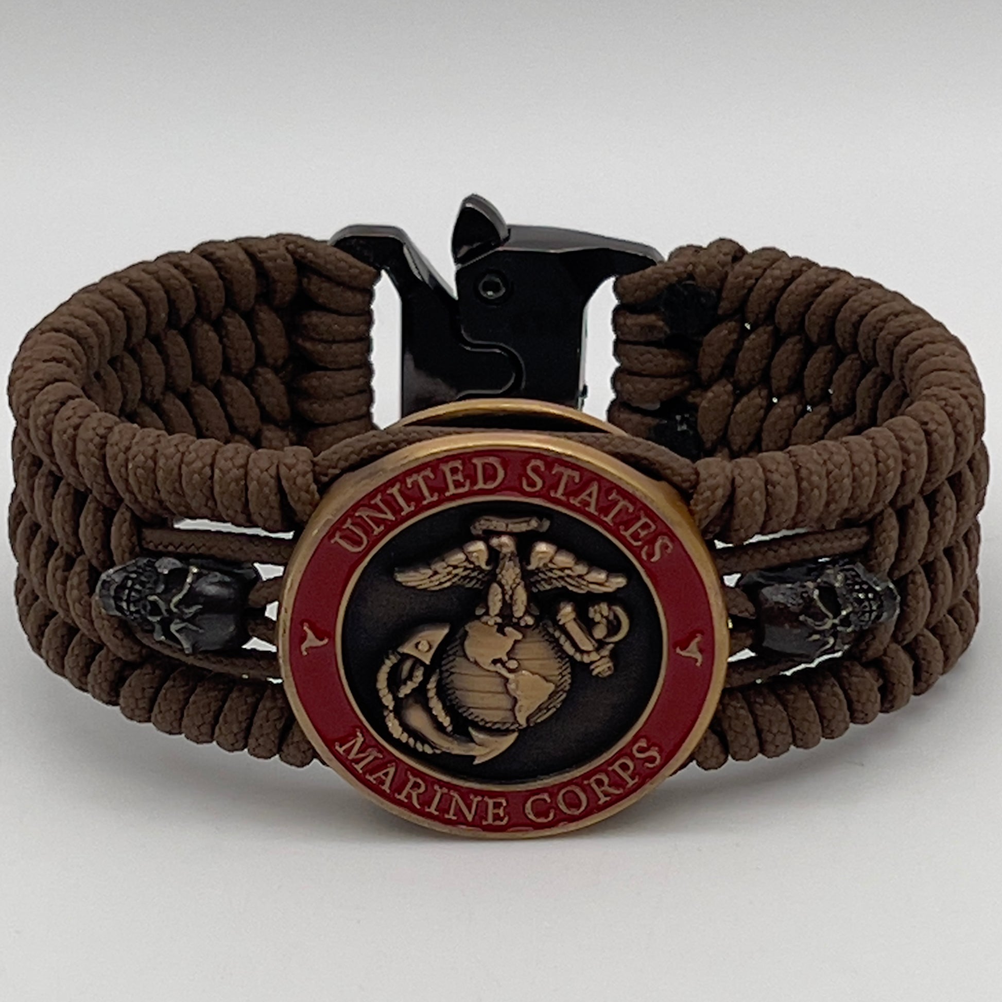 Thin, medium width, flexible and comfortable braided United States Marine Corps bracelet featuring a 24K antique gold plated USMC officer Eagle Globe and Anchor medallion, two black skulls, a black Cobra style tactical buckle and woven with Coyote Brown Type-1 paracord.