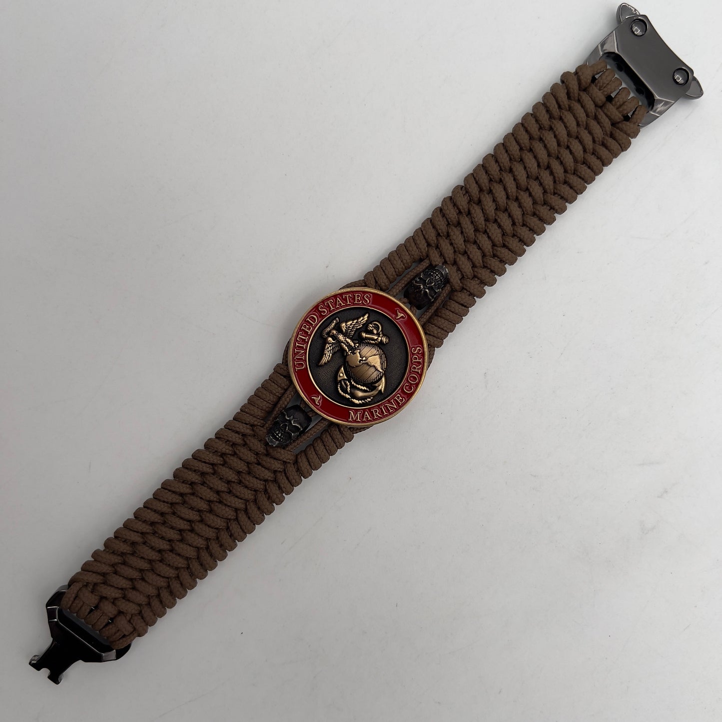 Thin, medium width, flexible and comfortable braided United States Marine Corps bracelet featuring a 24K antique gold plated USMC officer Eagle Globe and Anchor medallion, two black skulls, a black Cobra style tactical buckle and woven with Coyote Brown Type-1 paracord.