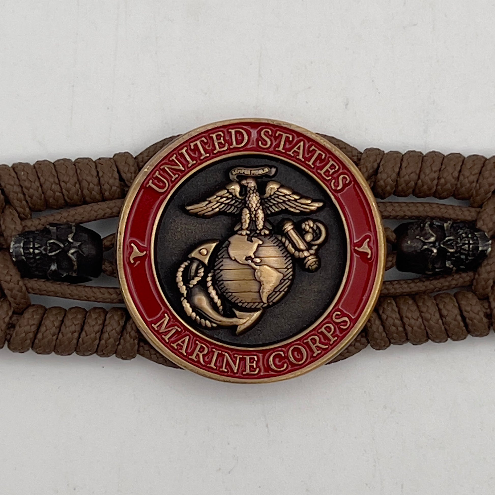 Thin, medium width, flexible and comfortable braided United States Marine Corps bracelet featuring a 24K antique gold plated USMC officer Eagle Globe and Anchor medallion, two black skulls, a black Cobra style tactical buckle and woven with Coyote Brown Type-1 paracord.
