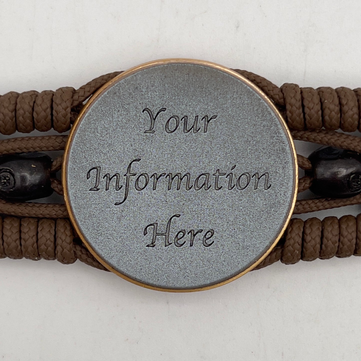 Thin, medium width, flexible and comfortable braided United States Marine Corps bracelet featuring a 24K antique gold plated USMC officer Eagle Globe and Anchor medallion, two black skulls, a black Cobra style tactical buckle and woven with Coyote Brown Type-1 paracord.