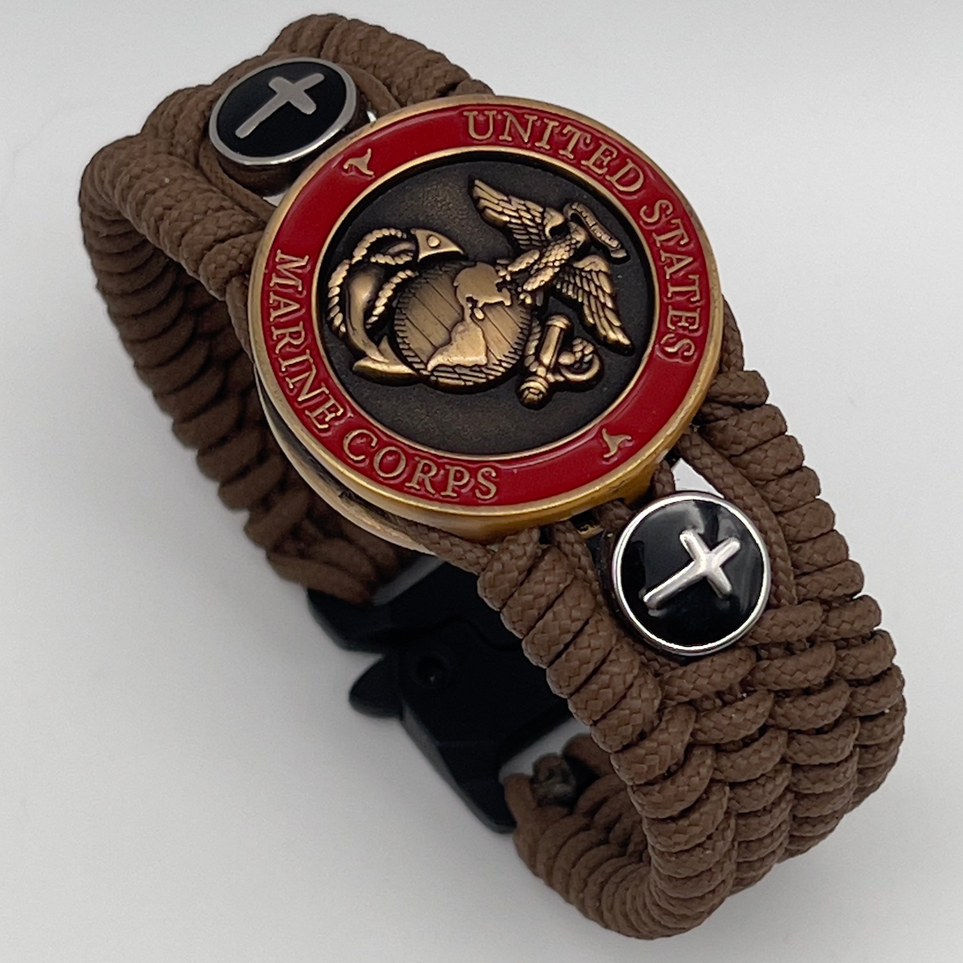 Thin, medium width, flexible and comfortable braided United States Marine Corps bracelet featuring a 24K antique gold plated USMC officer Eagle Globe and Anchor medallion, two Christian crosses, a black Cobra style tactical buckle and woven with Coyote Brown Type-1 paracord.