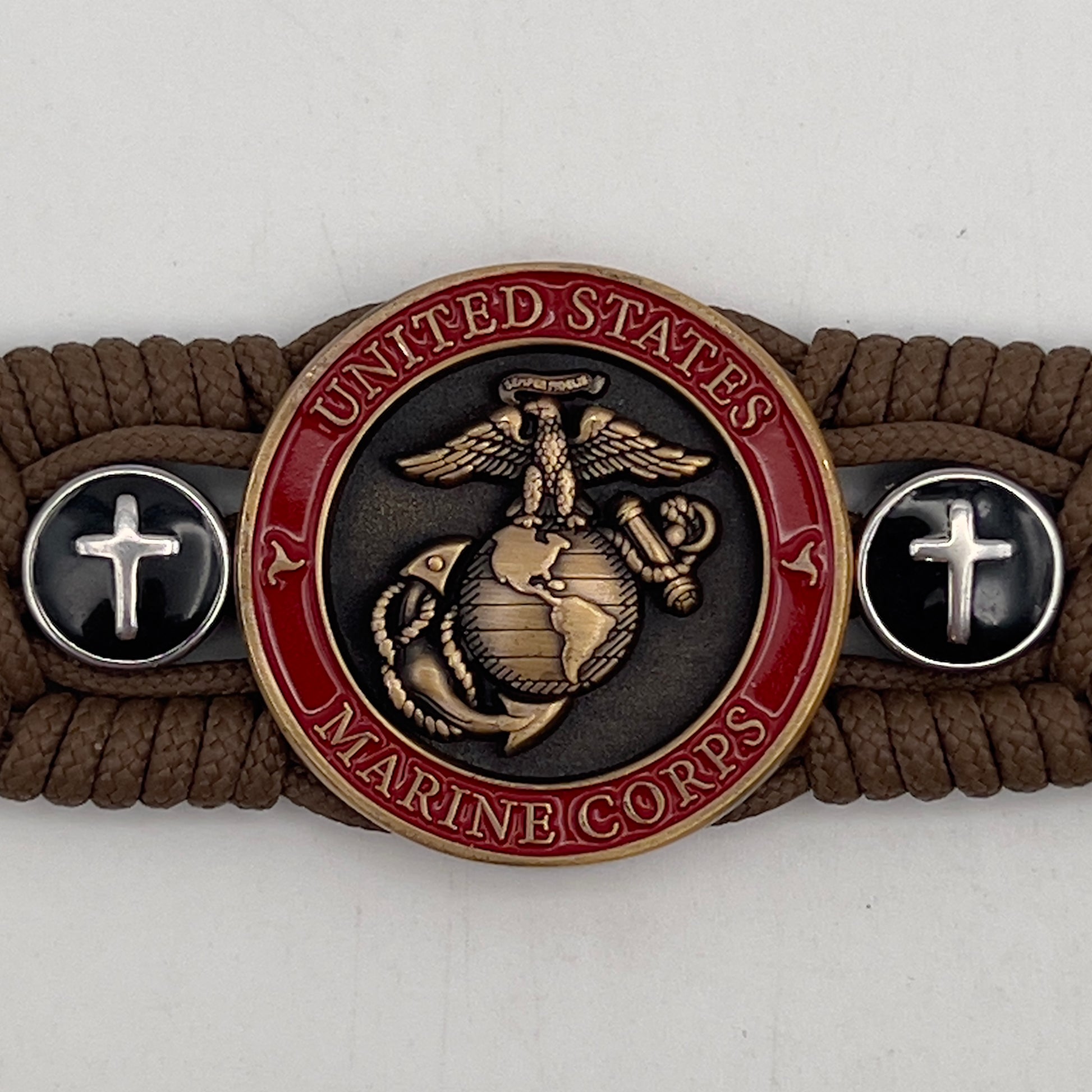 Thin, medium width, flexible and comfortable braided United States Marine Corps bracelet featuring a 24K antique gold plated USMC officer Eagle Globe and Anchor medallion, two Christian crosses, a black Cobra style tactical buckle and woven with Coyote Brown Type-1 paracord.