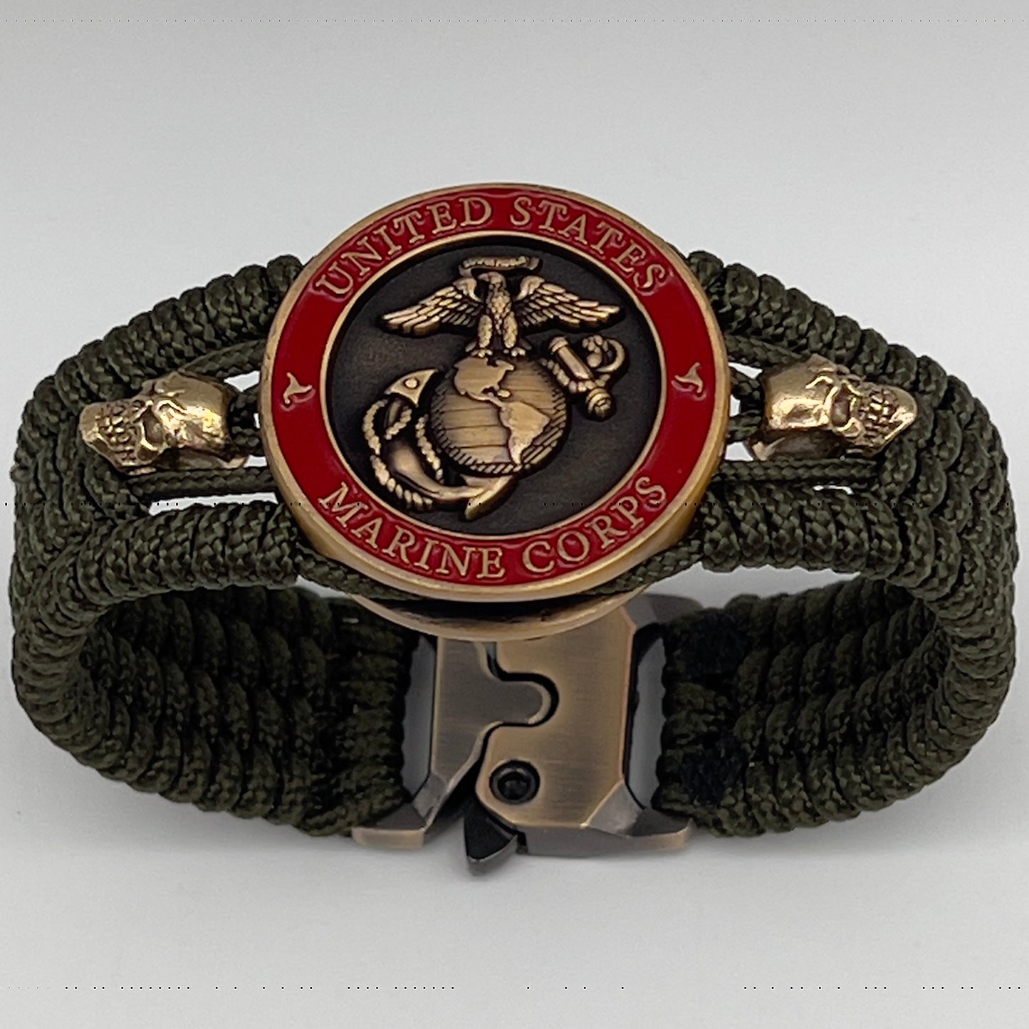 Thin, medium width, flexible and comfortable braided United States Marine Corps bracelet featuring a 24K antique gold plated USMC officer Eagle Globe and Anchor medallion, two gold plated skulls, a gold Cobra style tactical buckle and woven with Olive Drab Type-1 paracord.