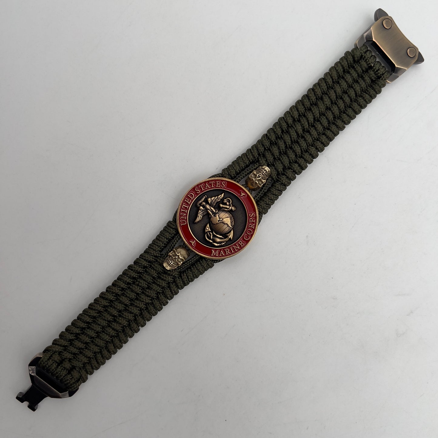 Thin, medium width, flexible and comfortable braided United States Marine Corps bracelet featuring a 24K antique gold plated USMC officer Eagle Globe and Anchor medallion, two gold plated skulls, a gold Cobra style tactical buckle and woven with Olive Drab Type-1 paracord.