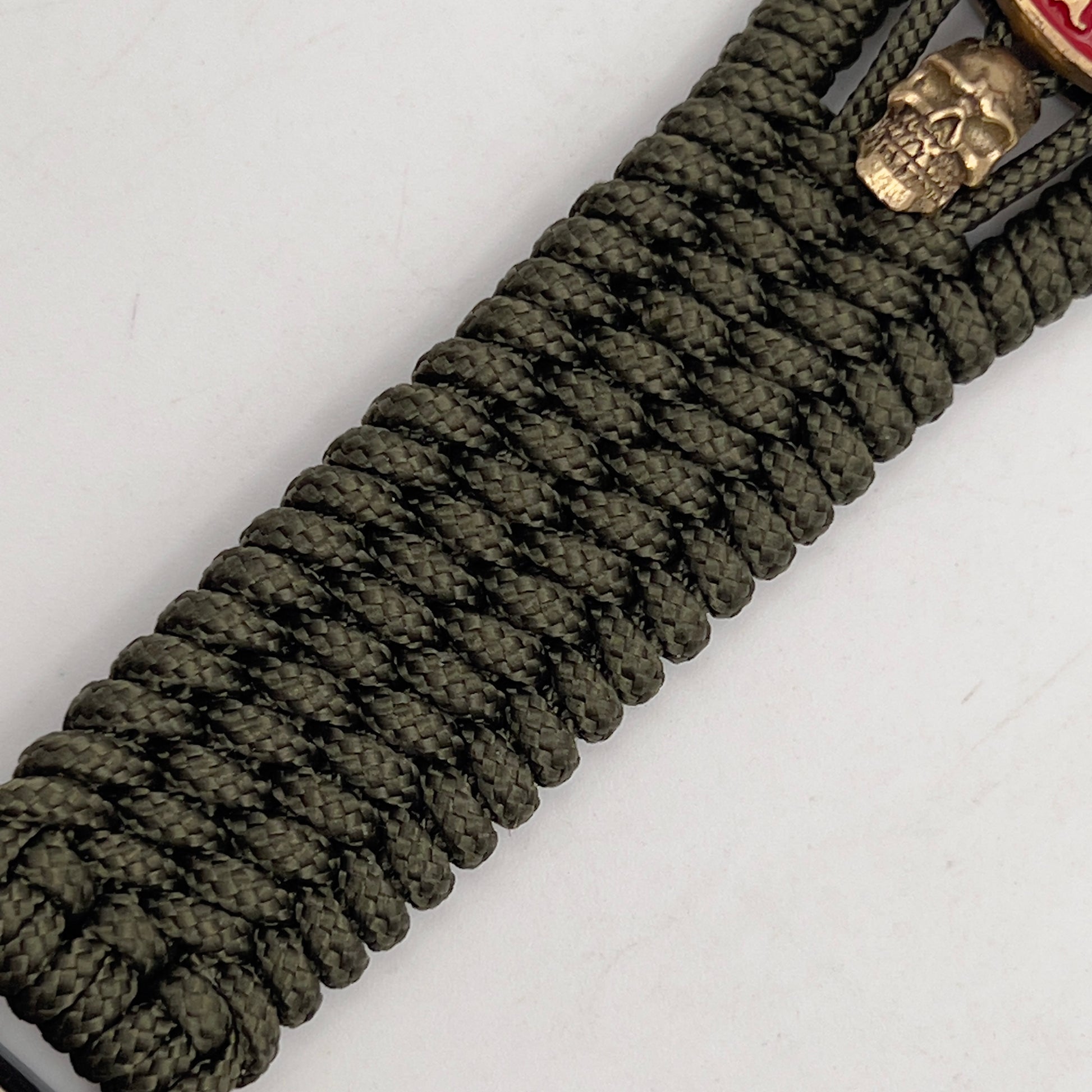 Thin, medium width, flexible and comfortable braided United States Marine Corps bracelet featuring a 24K antique gold plated USMC officer Eagle Globe and Anchor medallion, two gold plated skulls, a gold Cobra style tactical buckle and woven with Olive Drab Type-1 paracord.
