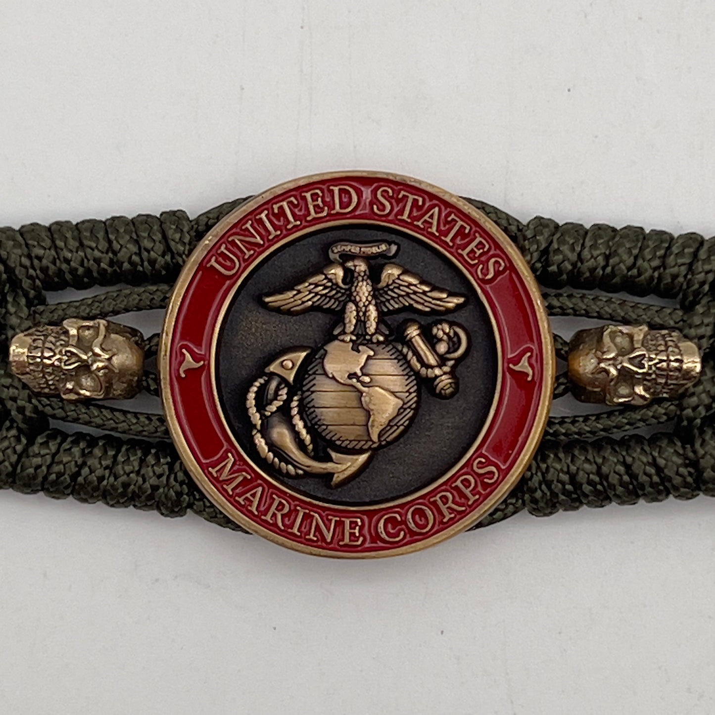 Thin, medium width, flexible and comfortable braided United States Marine Corps bracelet featuring a 24K antique gold plated USMC officer Eagle Globe and Anchor medallion, two gold plated skulls, a gold Cobra style tactical buckle and woven with Olive Drab Type-1 paracord.
