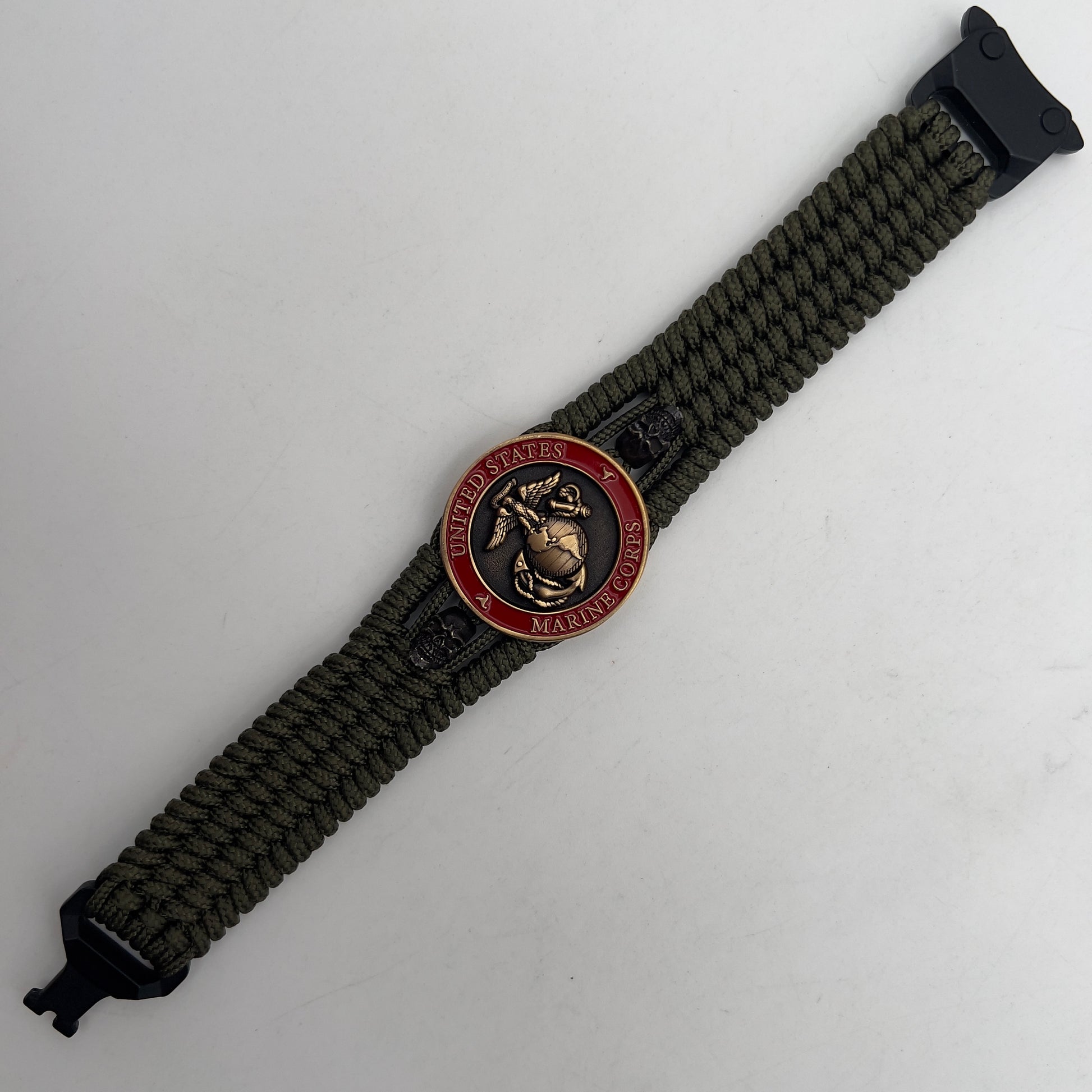 Thin, medium width, flexible and comfortable braided United States Marine Corps bracelet featuring a 24K antique gold plated USMC officer Eagle Globe and Anchor medallion, two black skulls, a black Cobra style tactical buckle and woven with Olive Drab Type-1 paracord.