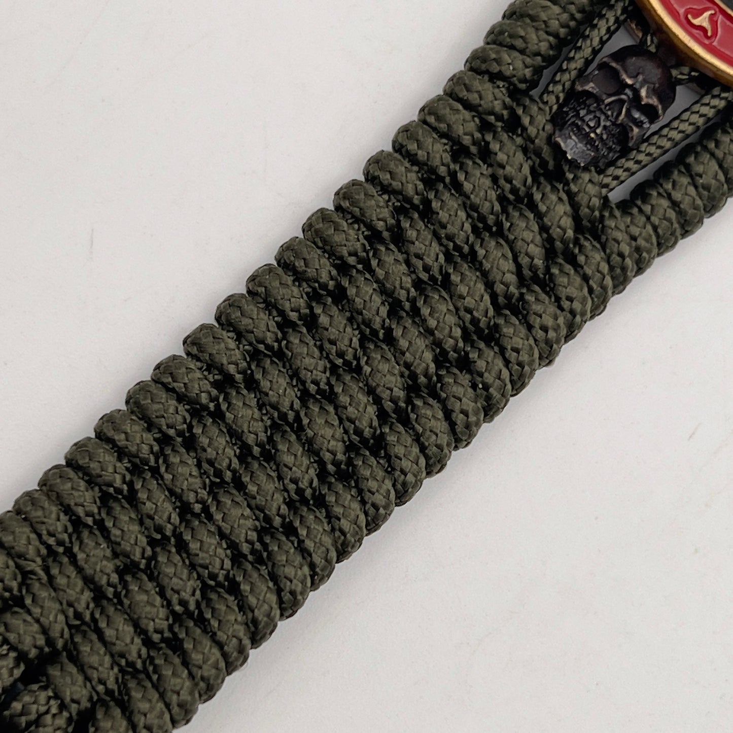 Thin, medium width, flexible and comfortable braided United States Marine Corps bracelet featuring a 24K antique gold plated USMC officer Eagle Globe and Anchor medallion, two black skulls, a black Cobra style tactical buckle and woven with Olive Drab Type-1 paracord.