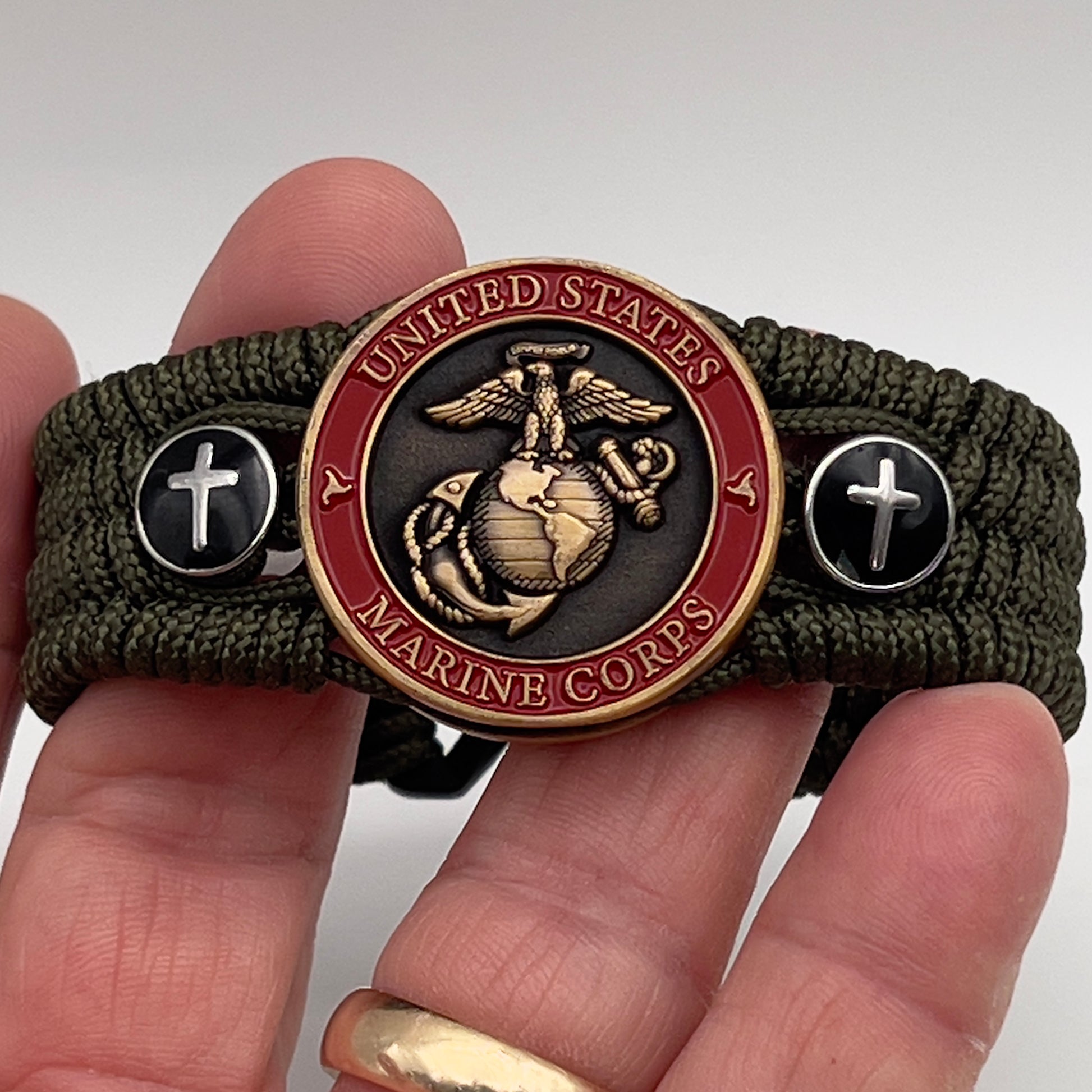 Thin, medium width, flexible and comfortable braided United States Marine Corps bracelet featuring a 24K antique gold plated USMC officer Eagle Globe and Anchor medallion, two Christian crosses, a black Cobra style tactical buckle and woven with Olive Drab Type-1 paracord.