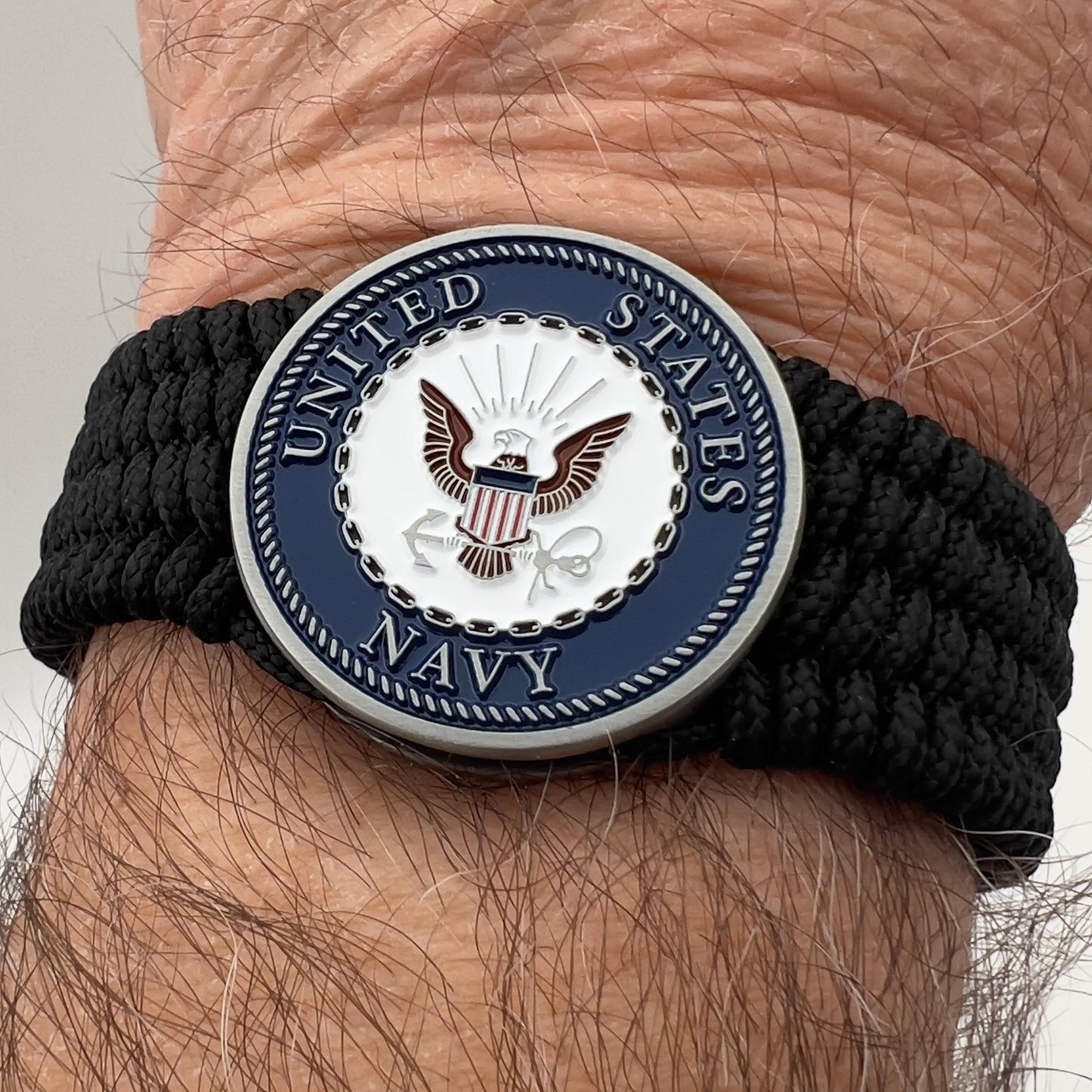 Thin, wide, flexible and comfortable braided United States Navy bracelet featuring an antique silver plated Navy medallion, a black Cobra style tactical buckle and woven with black Type-1 paracord.