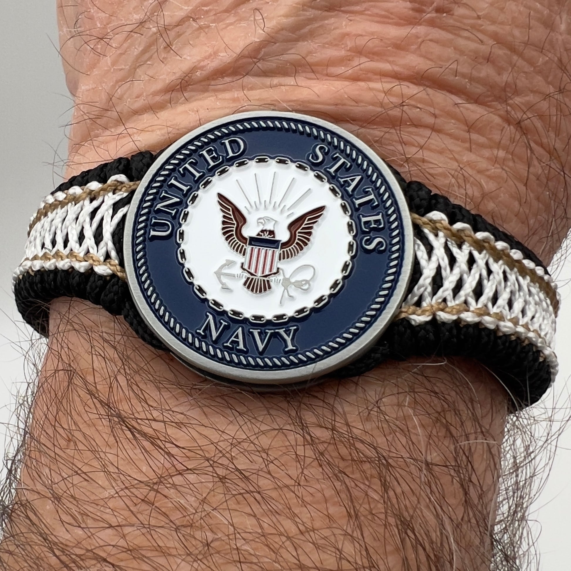 Thin, narrow, flexible and comfortable braided United States Marine Corps bracelet featuring an antique silver plated United States Navy medallion, a black Cobra style tactical buckle and woven with black Type-1 paracord and Gold adn White nano cord.