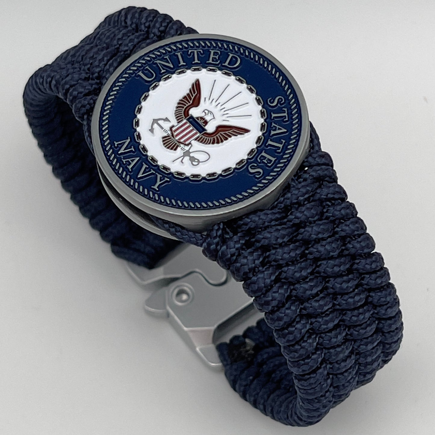 Thin, wide, flexible and comfortable braided United States Navy bracelet featuring an antique silver plated Navy medallion, a black Cobra style tactical buckle and woven with Navy Blue Type-1 paracord.