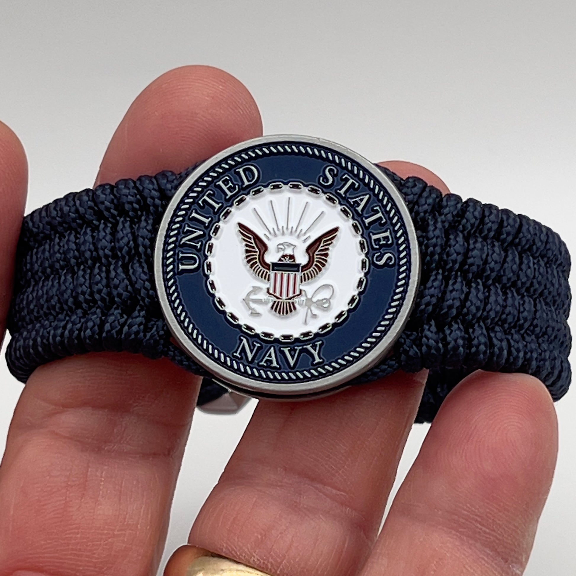 Thin, wide, flexible and comfortable braided United States Navy bracelet featuring an antique silver plated Navy medallion, a black Cobra style tactical buckle and woven with Navy Blue Type-1 paracord.