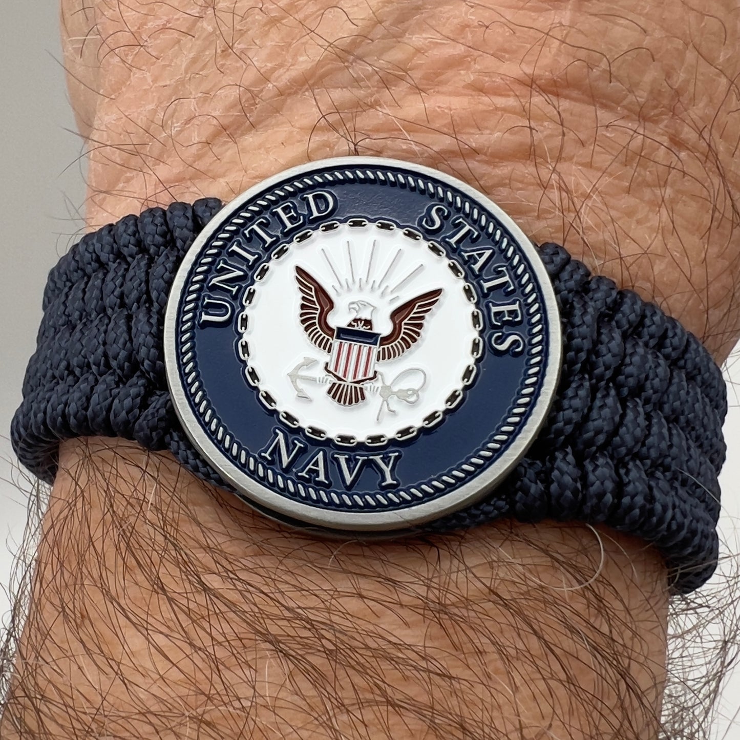 Thin, wide, flexible and comfortable braided United States Navy bracelet featuring an antique silver plated Navy medallion, a black Cobra style tactical buckle and woven with Navy Blue Type-1 paracord.