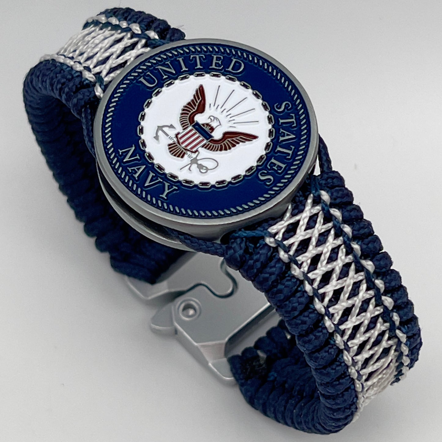 Thin, wide and comfortable braided United States Navy bracelet featuring an antique silver plated Navy medallion, a silver Cobra style tactical buckle and woven with Navy Blue Type-1 paracord and Nay Blue and White nano cord.