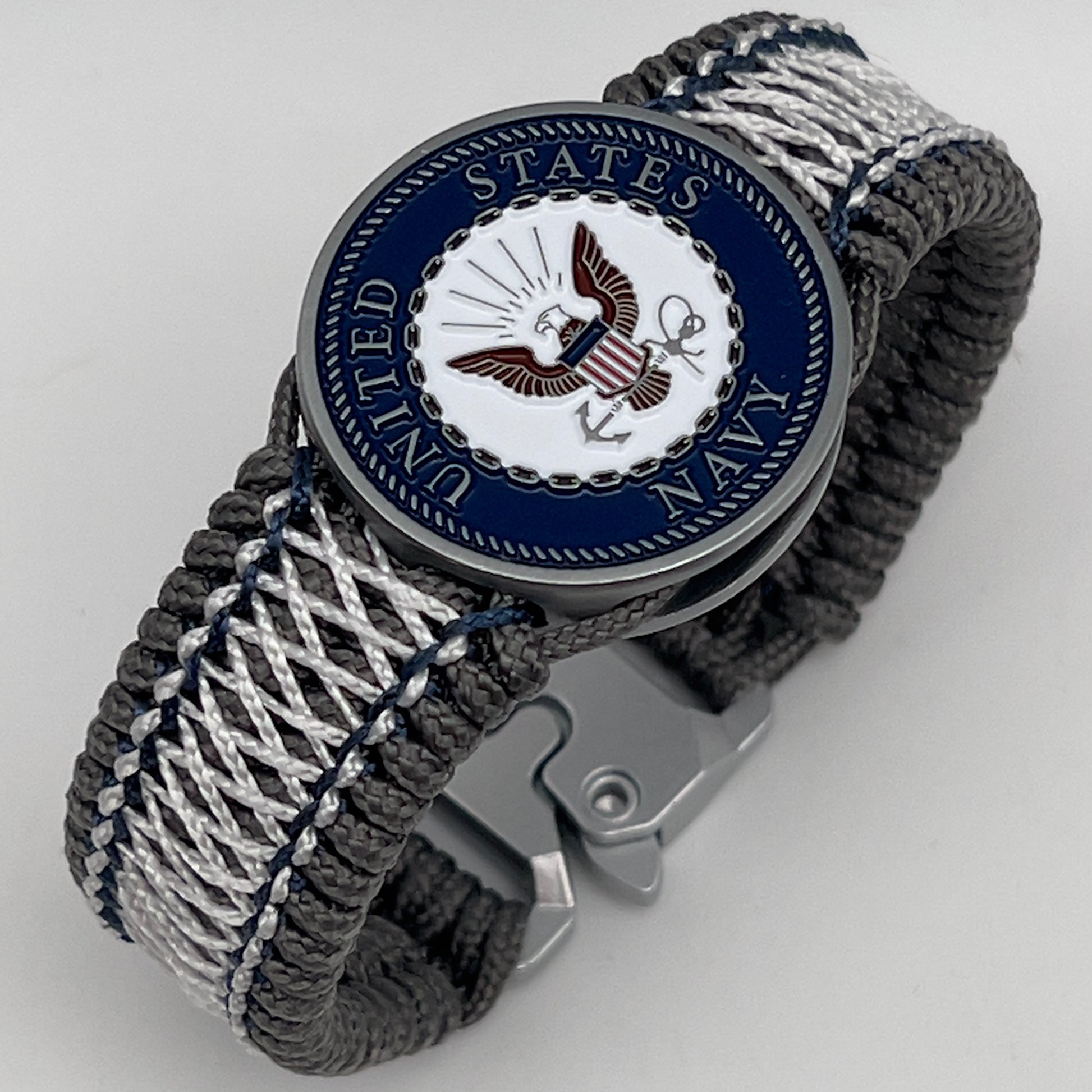 Thin, wide and comfortable braided United States Navy bracelet featuring an antique silver plated Navy medallion, a silver Cobra style tactical buckle and woven with Charcoal Gray Type-1 paracord and Nay Blue and White nano cord.