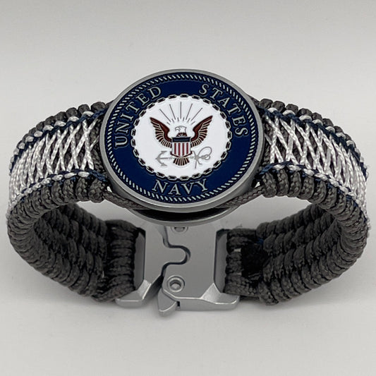 Thin, wide and comfortable braided United States Navy bracelet featuring an antique silver plated Navy medallion, a silver Cobra style tactical buckle and woven with Charcoal Gray Type-1 paracord and Nay Blue and White nano cord.