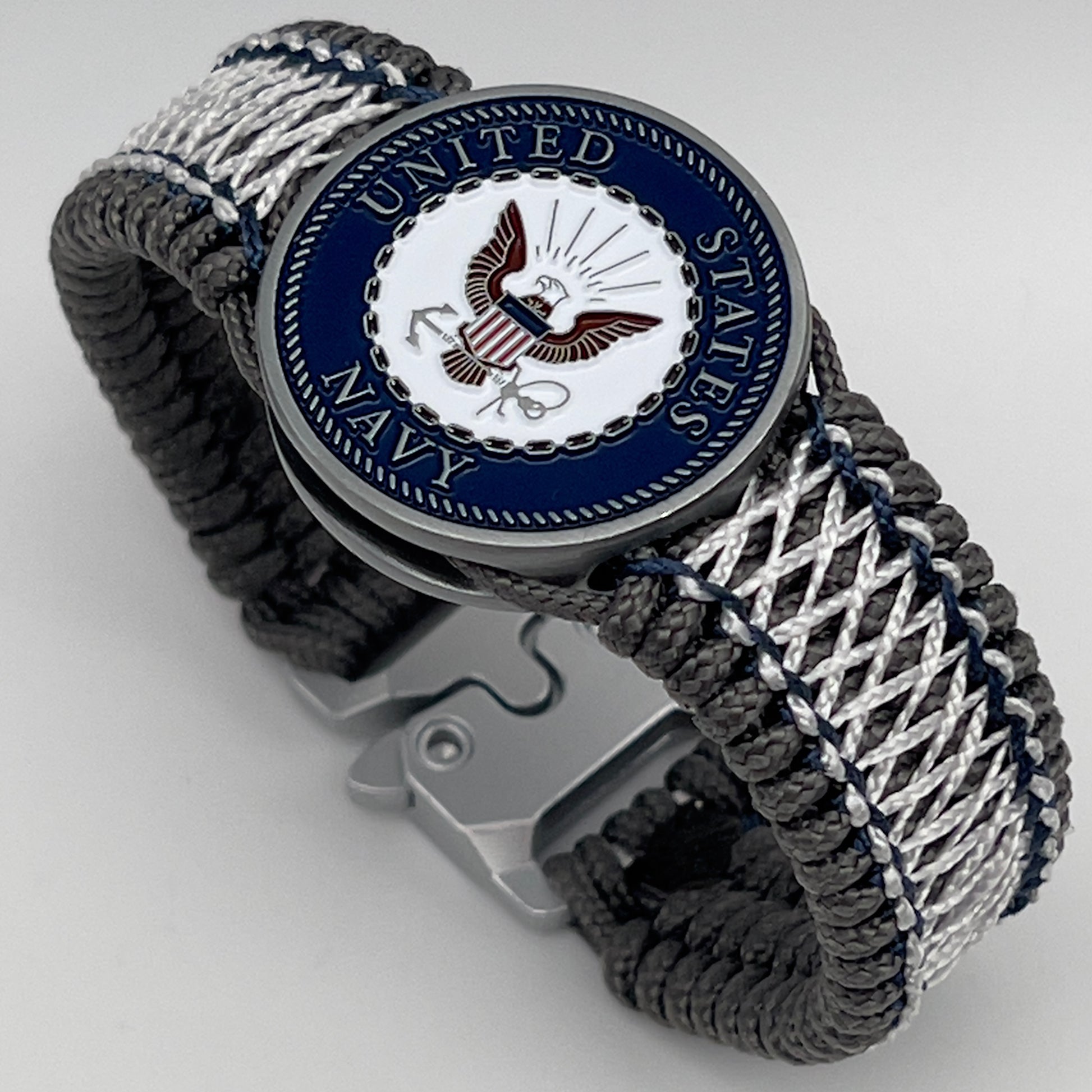 Thin, wide and comfortable braided United States Navy bracelet featuring an antique silver plated Navy medallion, a silver Cobra style tactical buckle and woven with Charcoal Gray Type-1 paracord and Nay Blue and White nano cord.