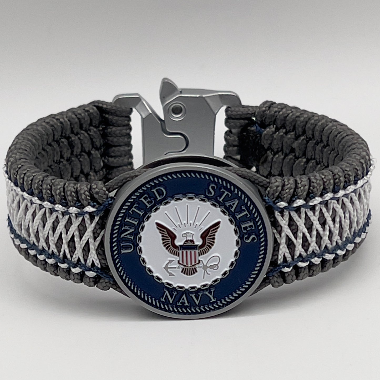 Thin, wide and comfortable braided United States Navy bracelet featuring an antique silver plated Navy medallion, a silver Cobra style tactical buckle and woven with Charcoal Gray Type-1 paracord and Nay Blue and White nano cord.