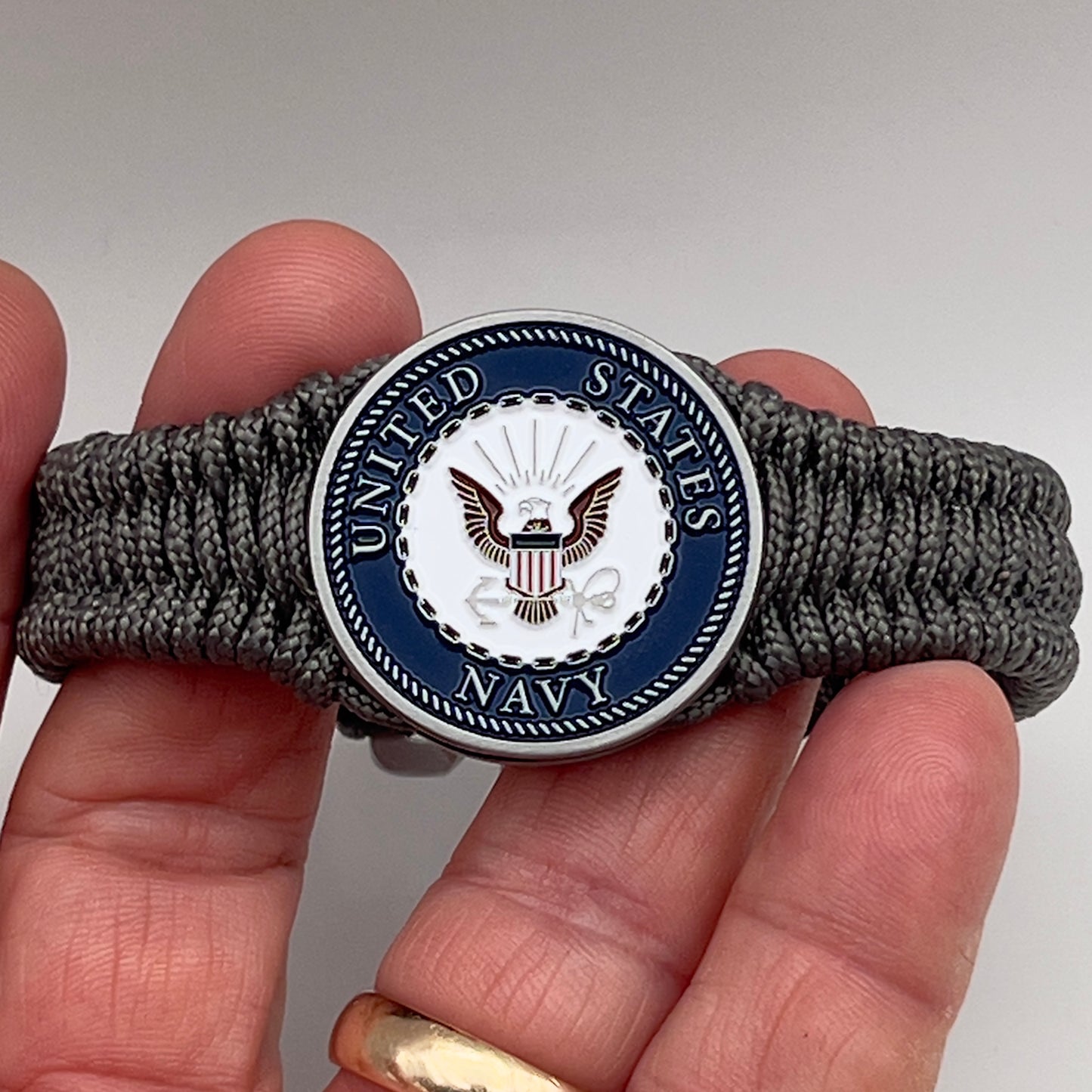 Thin, narrow, flexible and comfortable braided United States Navy bracelet featuring an antique silver plated Navy medallion, a silver Cobra style tactical buckle and woven with Charcoal Gray Type-1 paracord.
