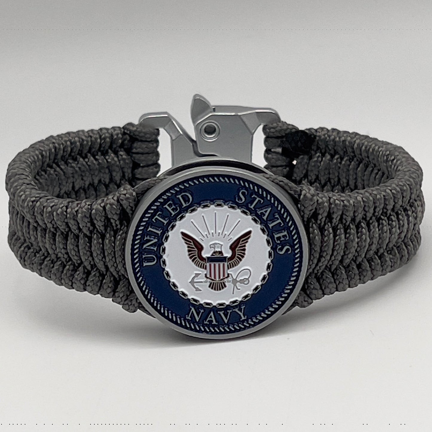 Thin, narrow, flexible and comfortable braided United States Navy bracelet featuring an antique silver plated Navy medallion, a silver Cobra style tactical buckle and woven with Charcoal Gray Type-1 paracord.