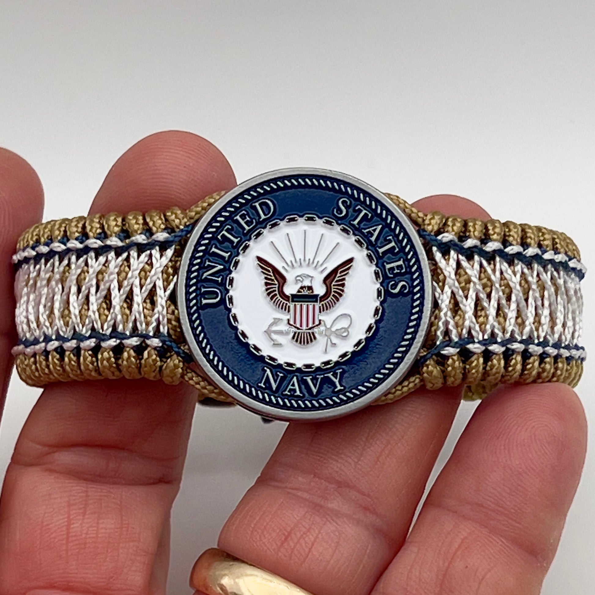 Thin, wide and comfortable braided United States Navy bracelet featuring an antique silver plated Navy medallion, a gold Cobra style tactical buckle and woven with gold Type-1 paracord and Navy Blue and White nano cord.