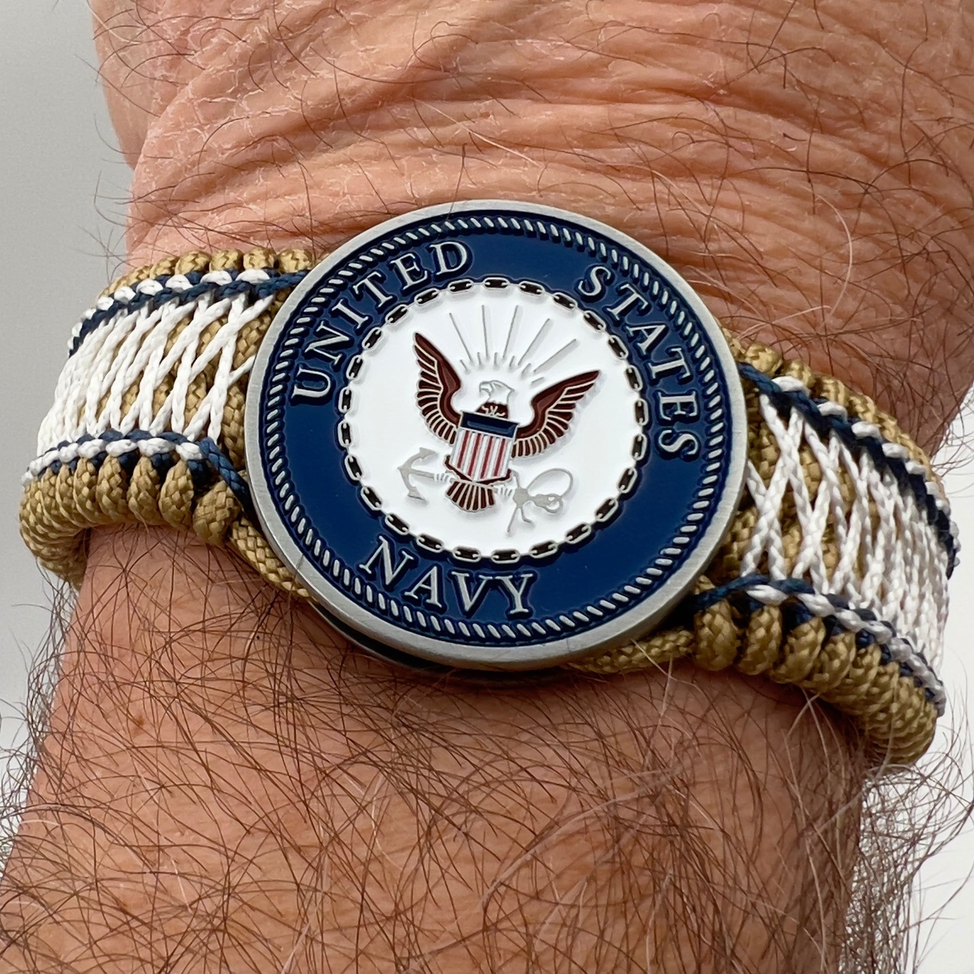 Thin, wide and comfortable braided United States Navy bracelet featuring an antique silver plated Navy medallion, a gold Cobra style tactical buckle and woven with gold Type-1 paracord and Navy Blue and White nano cord.