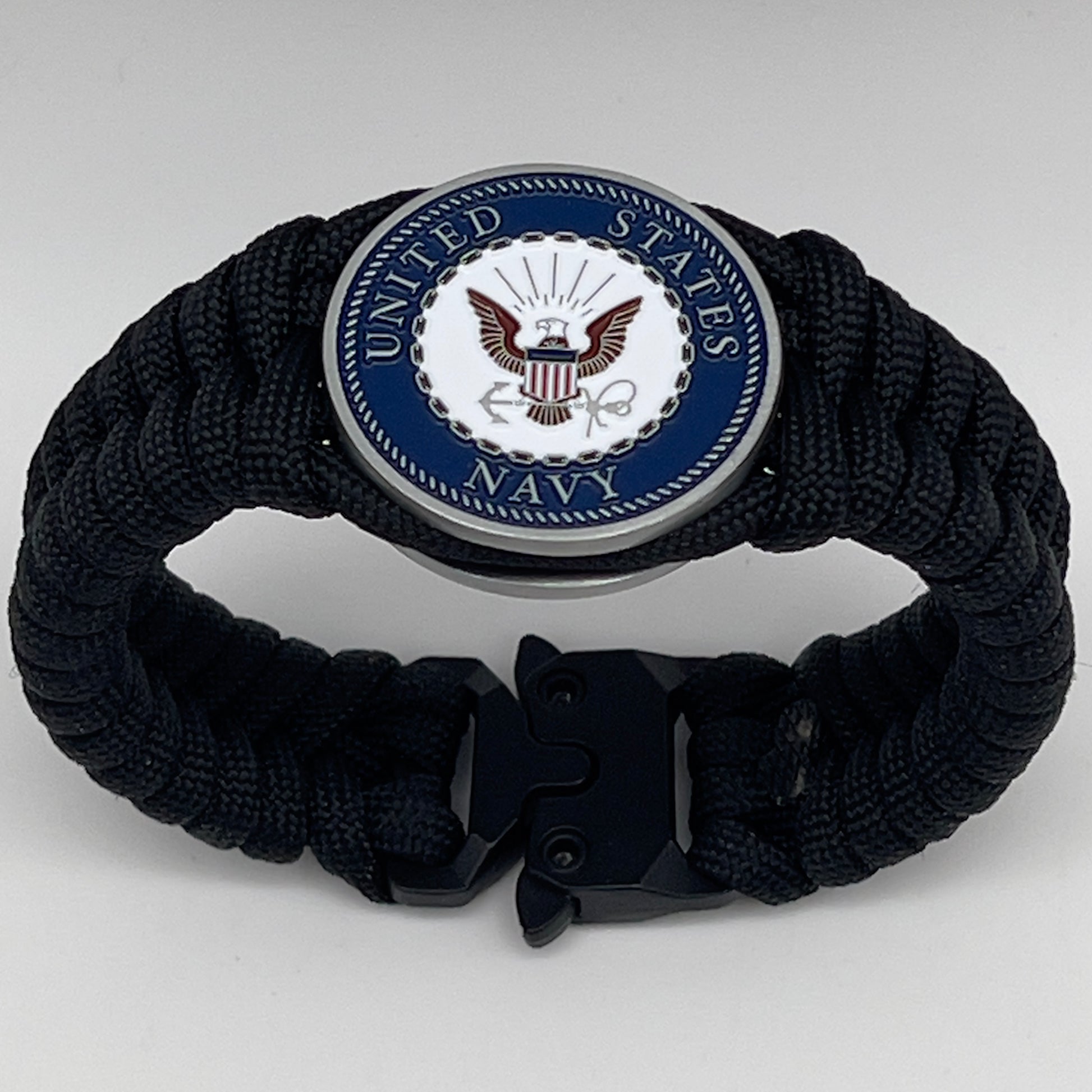 Thick, narrow, and semi-rigid braided United States Navy bracelet featuring an antique silver plated Navy medallion, a black Cobra style tactical buckle and woven with black 550 paracord.