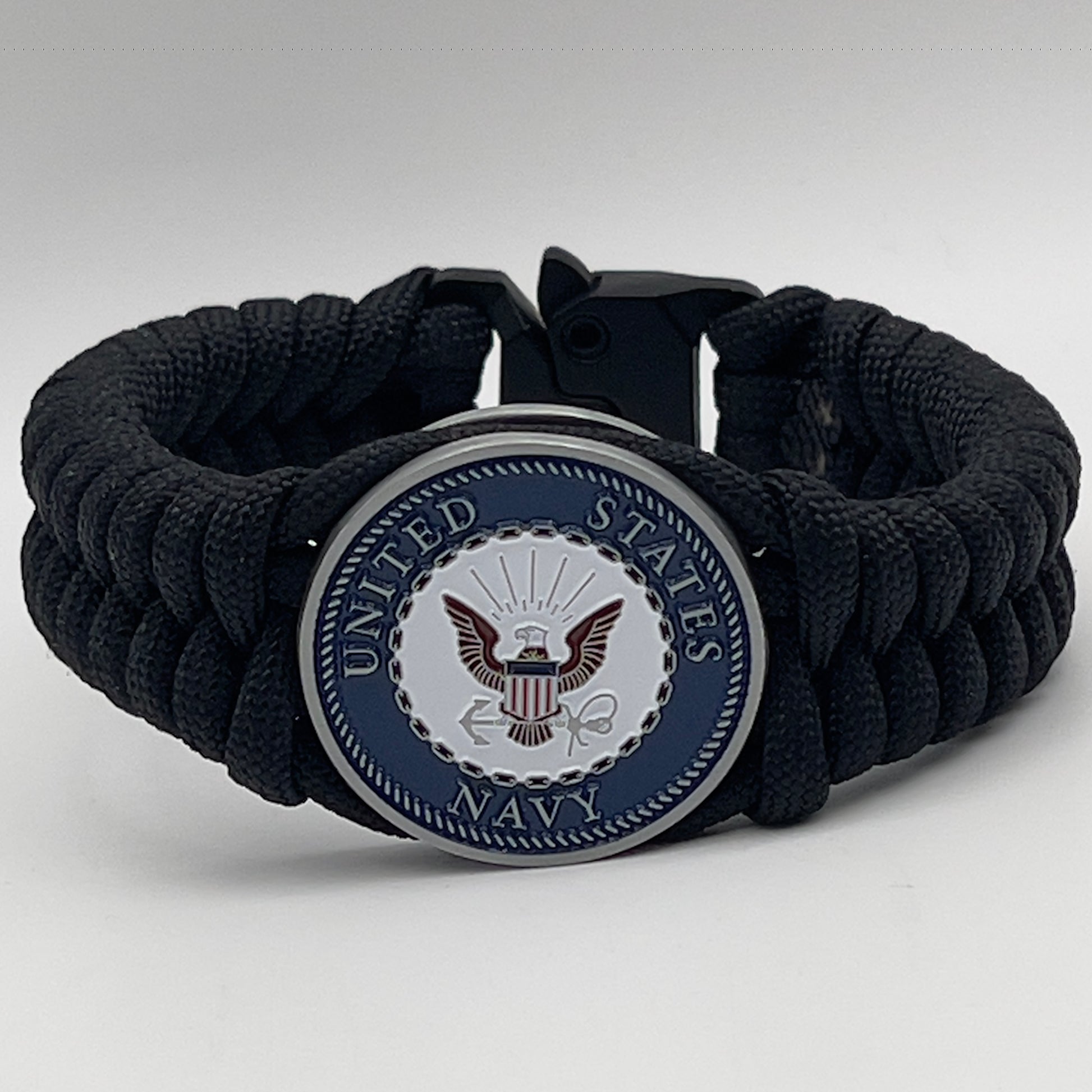 Thick, narrow, and semi-rigid braided United States Navy bracelet featuring an antique silver plated Navy medallion, a black Cobra style tactical buckle and woven with black 550 paracord.
