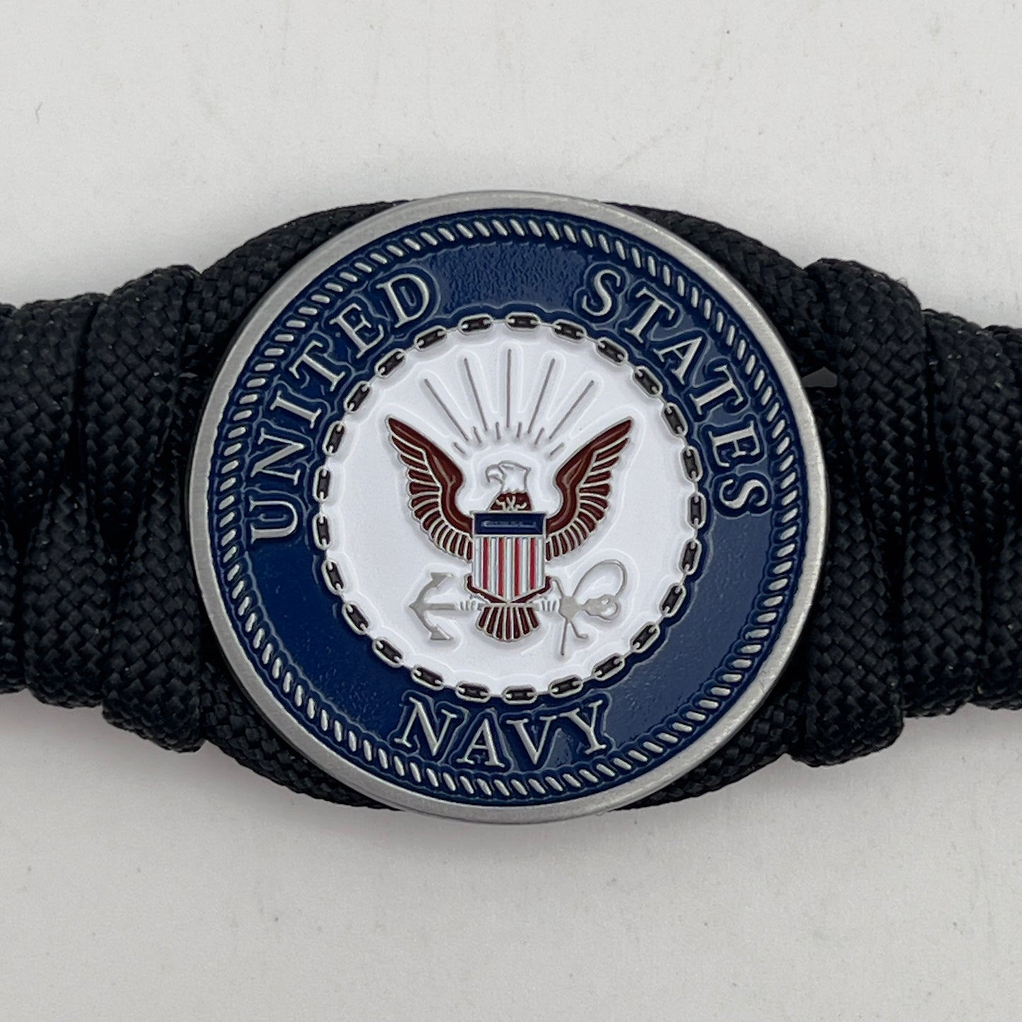 Thick, narrow, and semi-rigid braided United States Navy bracelet featuring an antique silver plated Navy medallion, a black Cobra style tactical buckle and woven with black 550 paracord.