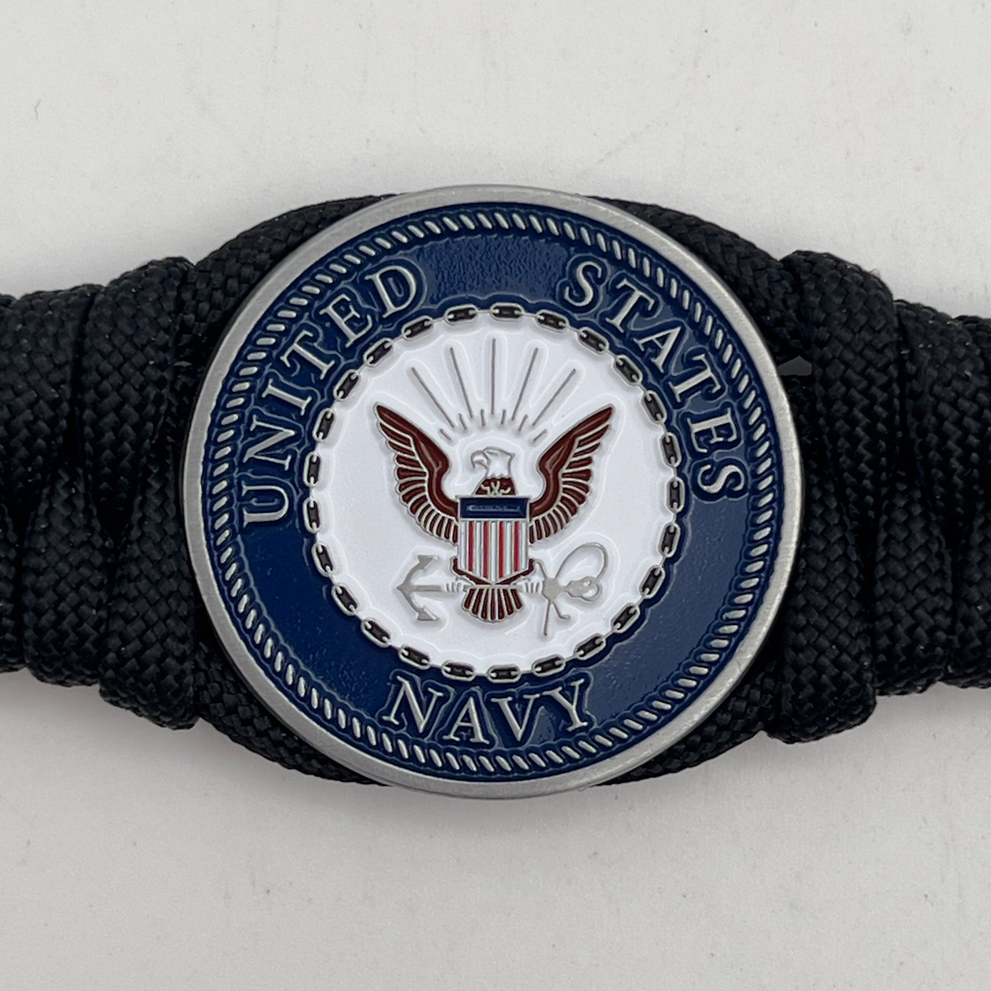 Thick, narrow, and semi-rigid braided United States Navy bracelet featuring an antique silver plated Navy medallion, a black Cobra style tactical buckle and woven with black 550 paracord.