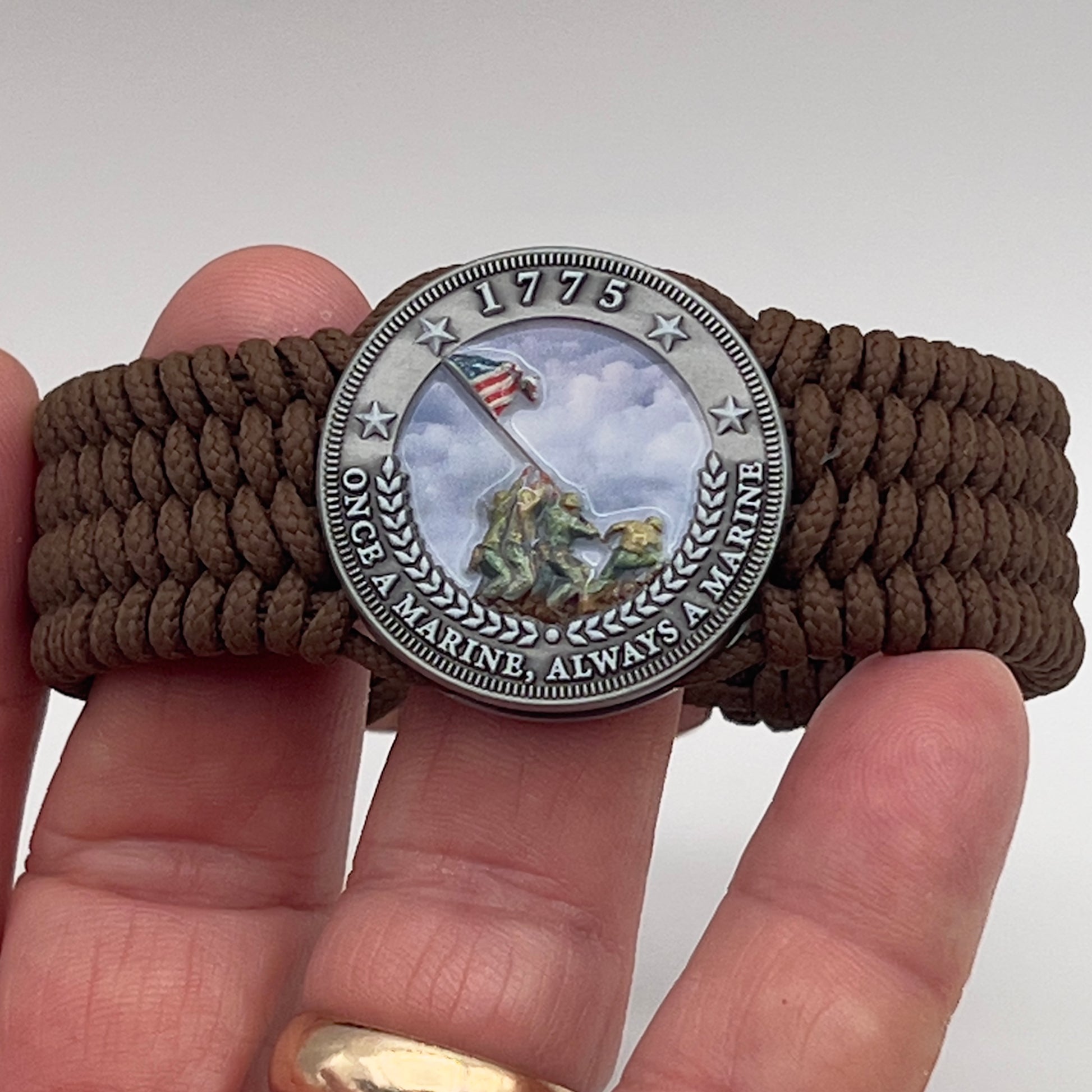 Thin, wide, flexible and comfortable braided United States Marine Corps Iwo Jima bracelet featuring an antique silver plated UV painted Iwo Jima flag raising medallion, a silver Cobra style tactical buckle and woven with Coyote Brown Type-1 paracord.