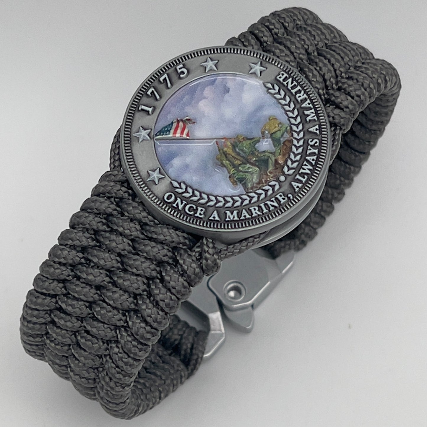Thin, wide, flexible and comfortable braided United States Marine Corps Iwo Jima bracelet featuring an antique silver plated Iwo Jima flag raising medallion, a silver Cobra style tactical buckle and woven with gray Type-1 paracord.