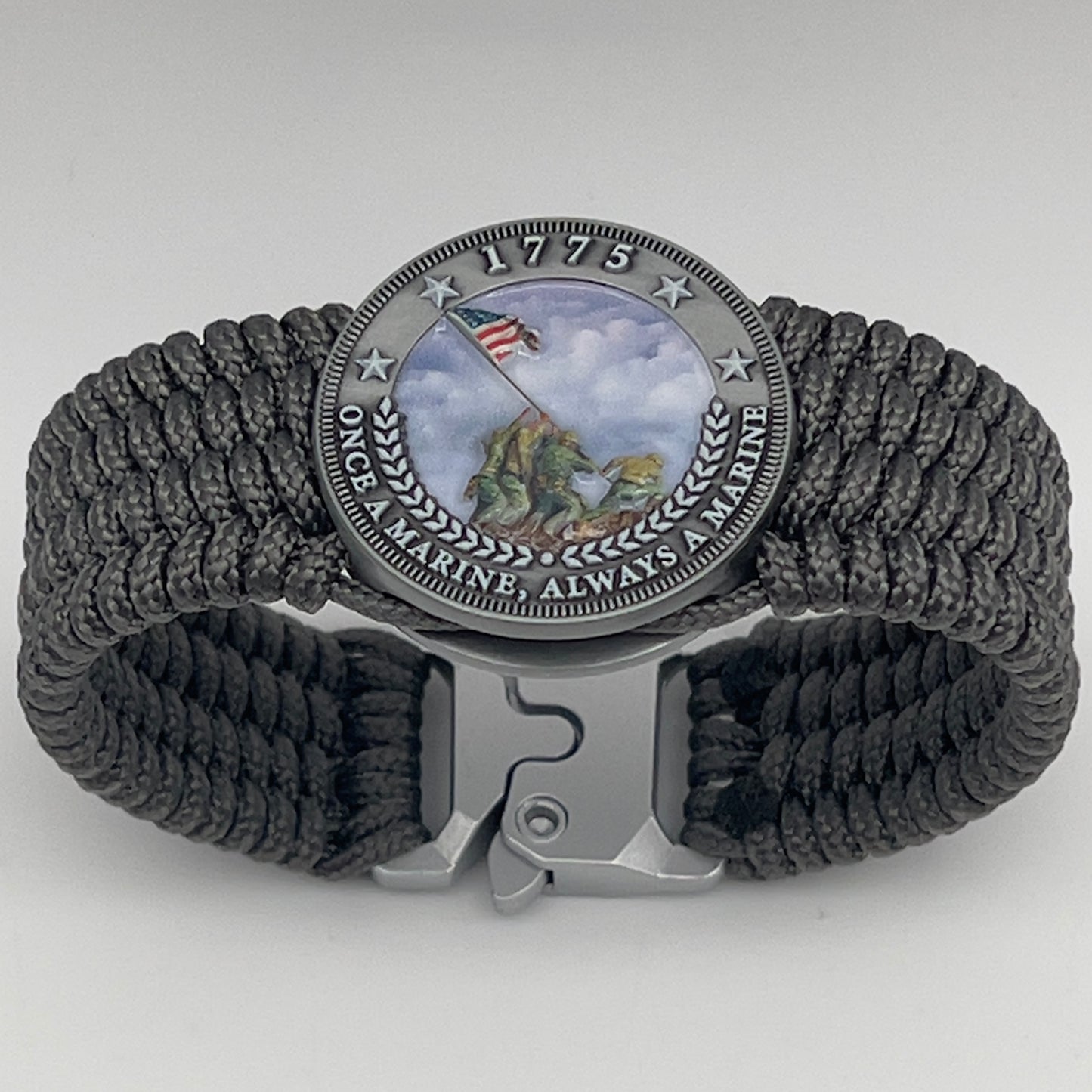 Thin, wide, flexible and comfortable braided United States Marine Corps Iwo Jima bracelet featuring an antique silver plated Iwo Jima flag raising medallion, a silver Cobra style tactical buckle and woven with gray Type-1 paracord.