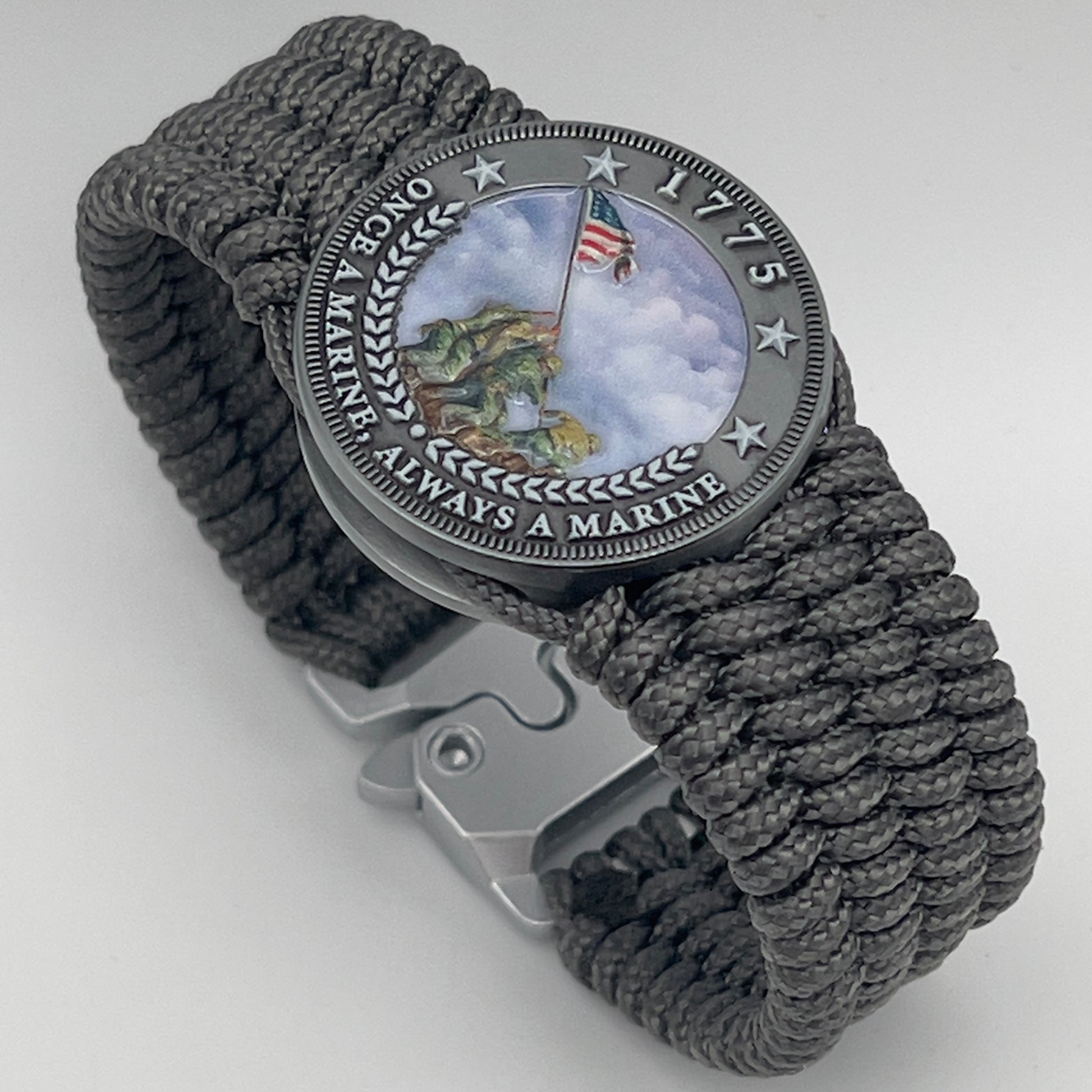 Thin, wide, flexible and comfortable braided United States Marine Corps Iwo Jima bracelet featuring an antique silver plated Iwo Jima flag raising medallion, a silver Cobra style tactical buckle and woven with gray Type-1 paracord.