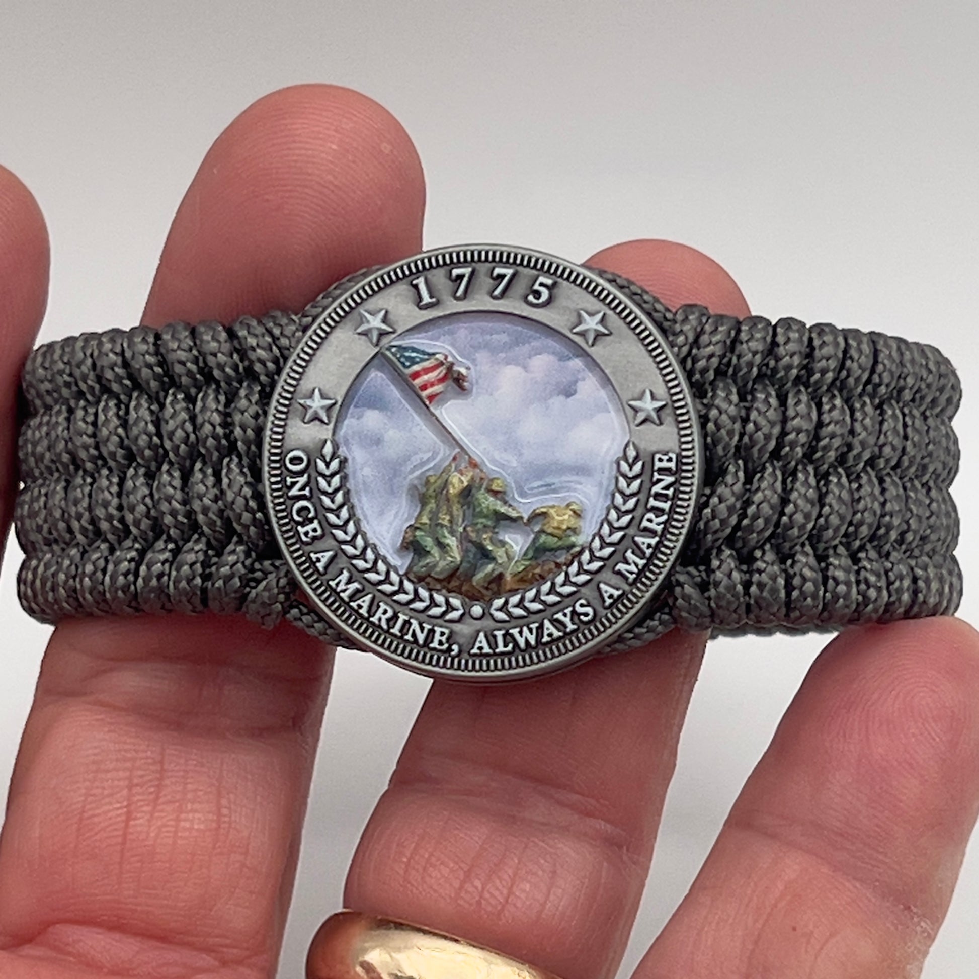 Thin, wide, flexible and comfortable braided United States Marine Corps Iwo Jima bracelet featuring an antique silver plated Iwo Jima flag raising medallion, a silver Cobra style tactical buckle and woven with gray Type-1 paracord.