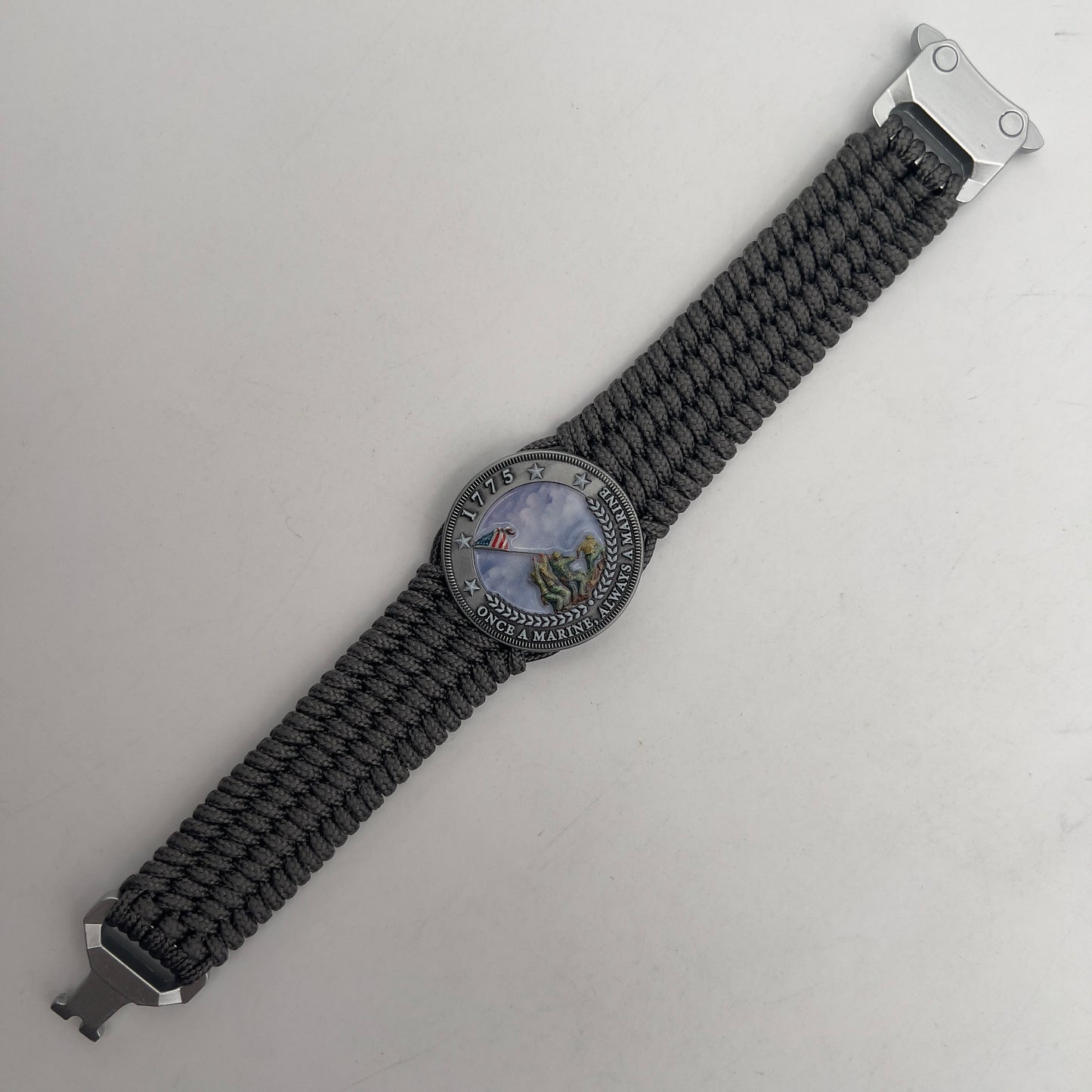 Thin, wide, flexible and comfortable braided United States Marine Corps Iwo Jima bracelet featuring an antique silver plated Iwo Jima flag raising medallion, a silver Cobra style tactical buckle and woven with gray Type-1 paracord.