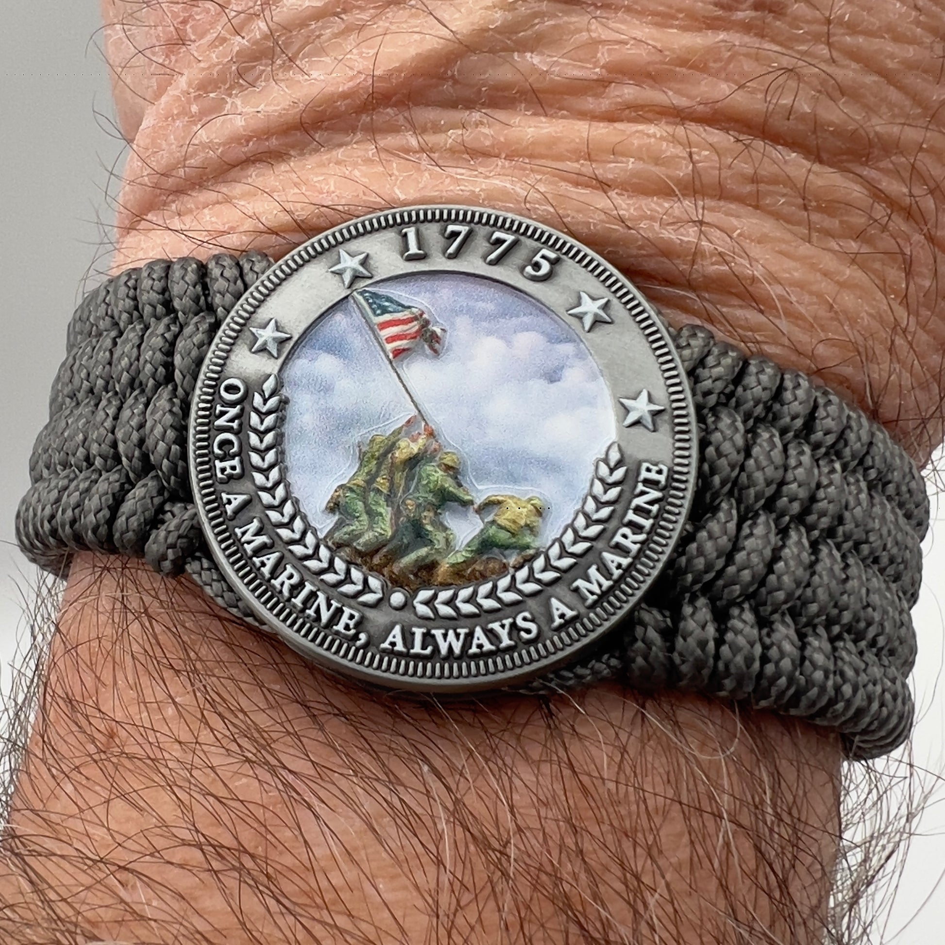 Thin, wide, flexible and comfortable braided United States Marine Corps Iwo Jima bracelet featuring an antique silver plated Iwo Jima flag raising medallion, a silver Cobra style tactical buckle and woven with gray Type-1 paracord.