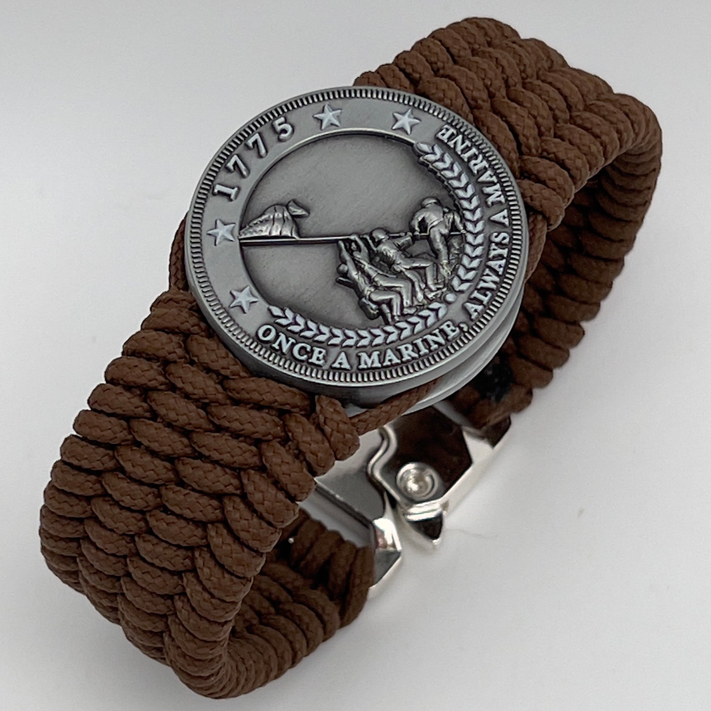 Thin, wide, flexible and comfortable braided United States Marine Corps Iwo Jima bracelet featuring an antique silver plated Iwo Jima flag raising medallion, a silver Cobra style tactical buckle and woven with Coyote Brown Type-1 paracord.