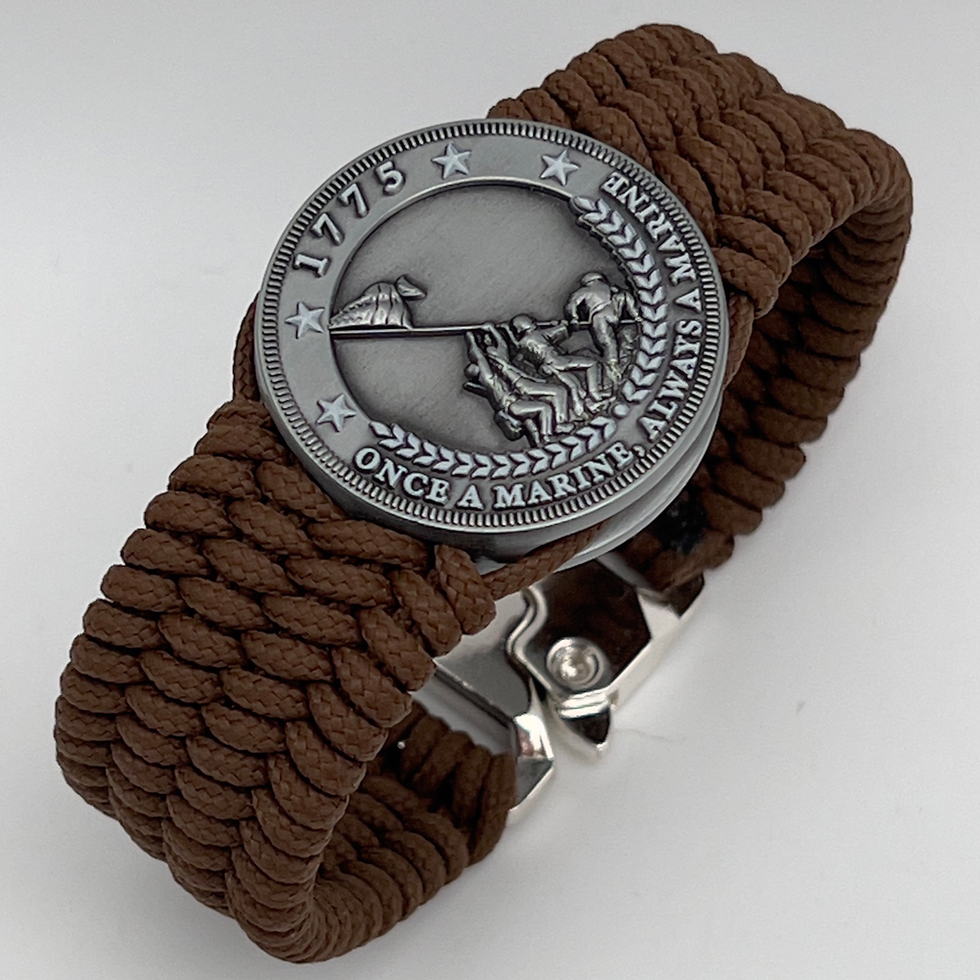Thin, wide, flexible and comfortable braided United States Marine Corps Iwo Jima bracelet featuring an antique silver plated Iwo Jima flag raising medallion, a silver Cobra style tactical buckle and woven with Coyote Brown Type-1 paracord.